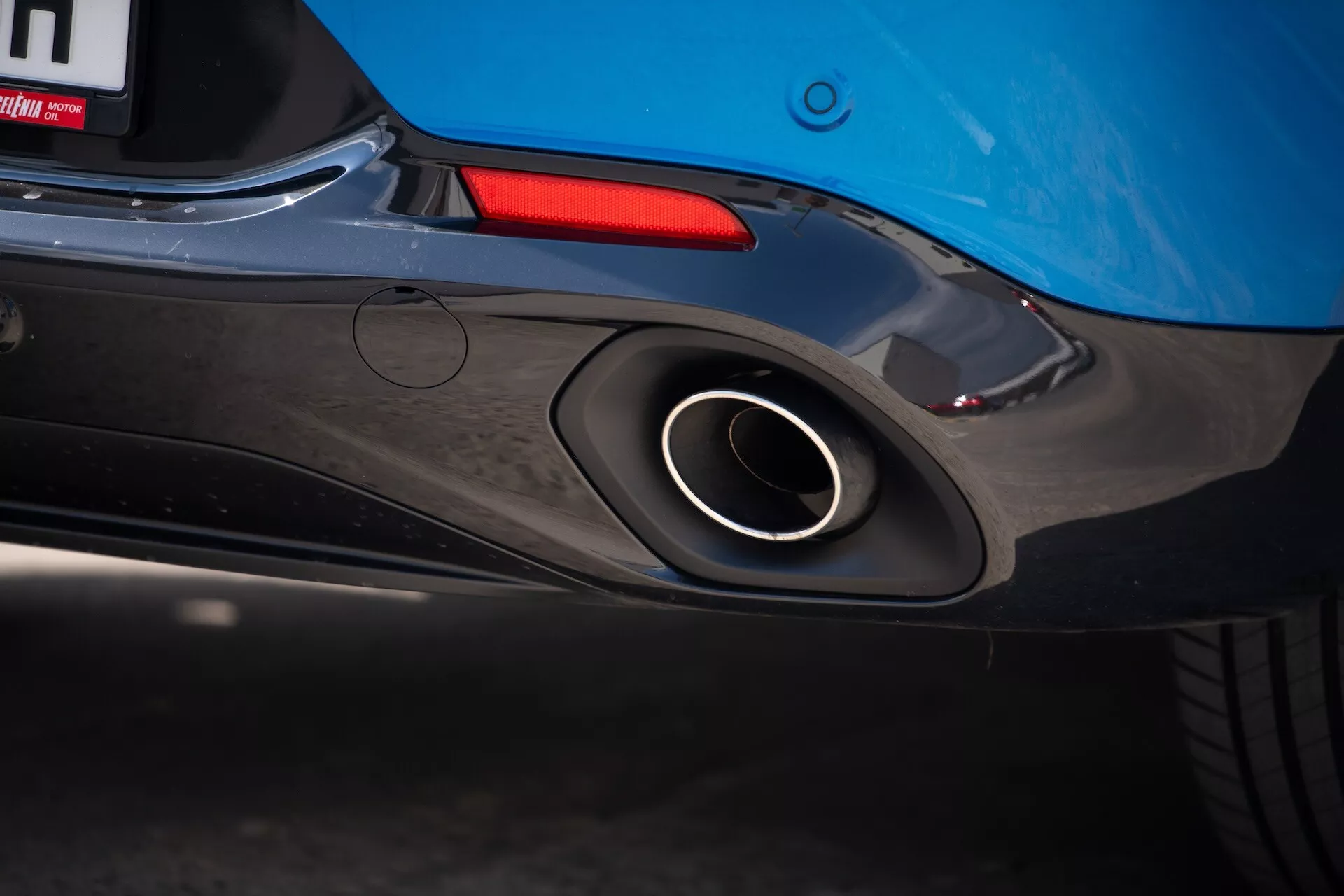 Podroben pogled na zadnji del Alfa Romeo Tonale 2022, ki poudarja športni izpušni lonec, aerodinamično zasnovo zadnjega odbijača in modro barvo karoserije z vpogledom na zadnjo luč