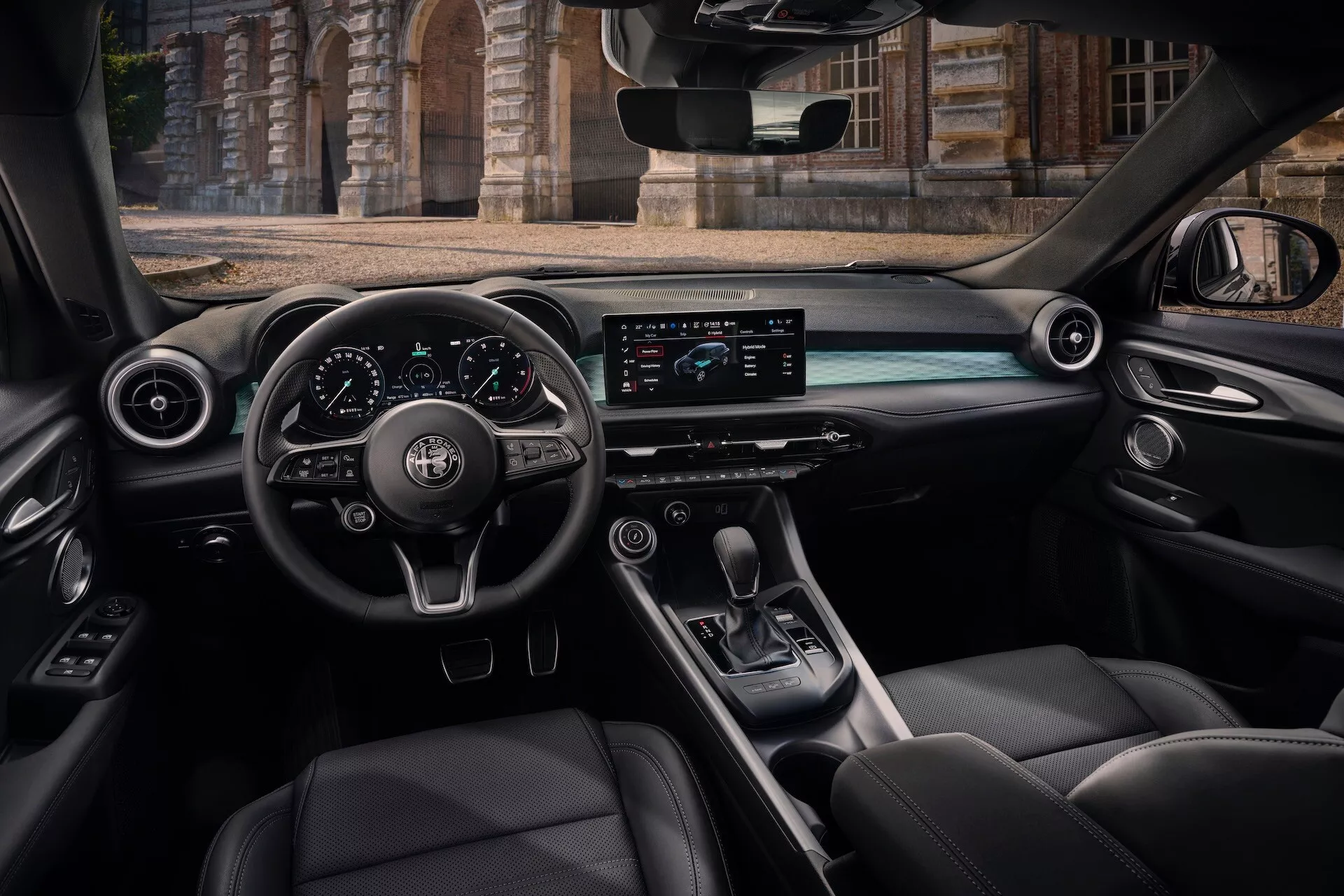 Notranjost Alfa Romeo Tonale 2022 iz perspektive zadnjega potniškega sedeža z kokpitom, volanom z upravljalnimi gumbi, digitalno armaturno ploščo, horizontalnim zaslonom za informacije in zabavo, sredinsko konzolo z izbirnikom prestav in razkošnimi usnjenimi sedeži