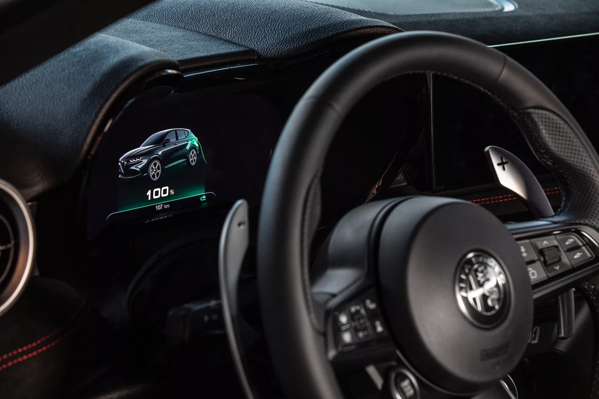 Notranjost Alfa Romeo Tonale 2022 s perspektive voznika s digitalnim armaturnim ploščo, multifunkcijskim volanom in indikatorji električnega vozila
