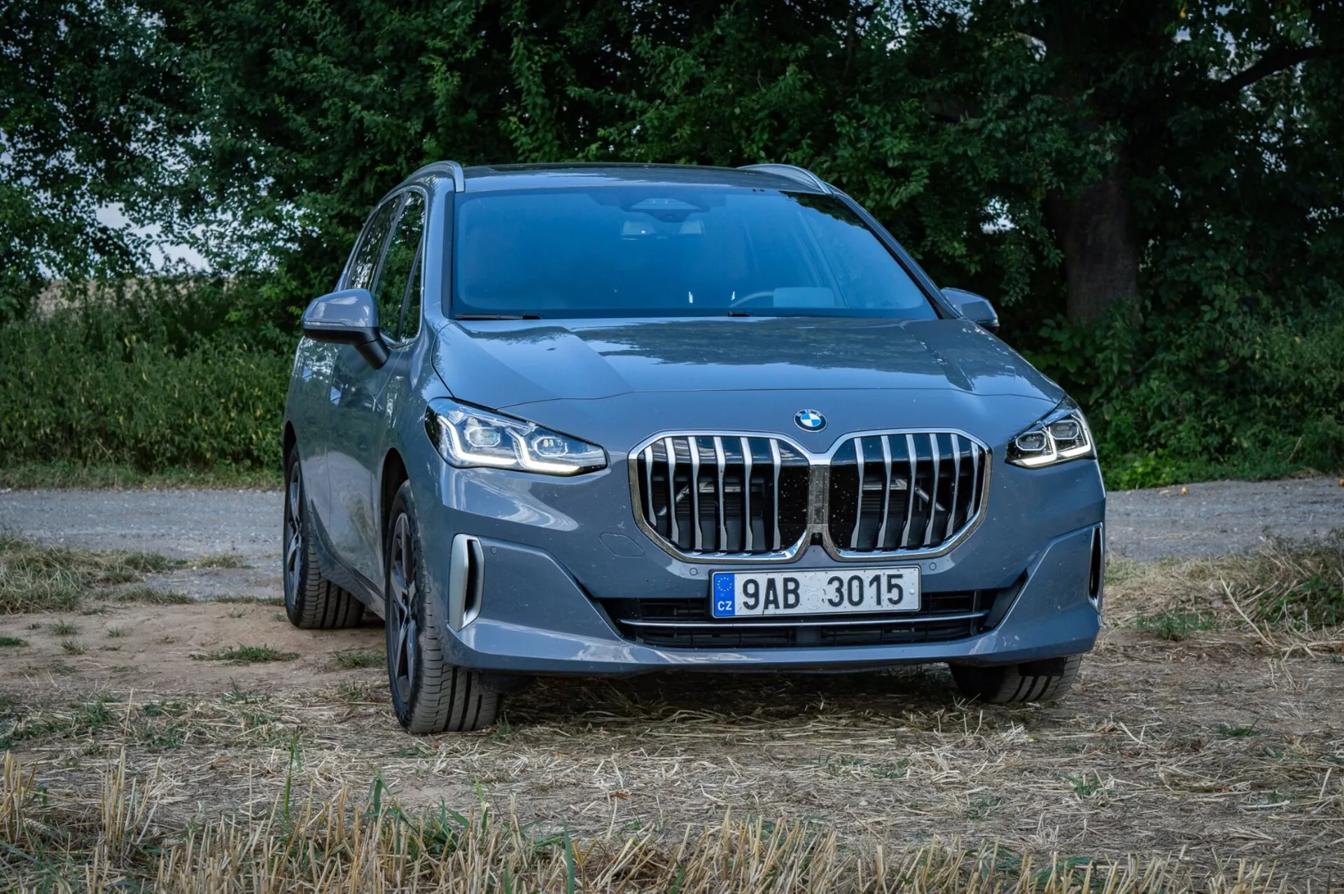 Modri SUV BMW serije 2 Active Tourer pod kotom sprednjih treh četrtin, ki prikazuje ikonično ledvičasto masko, LED žaromete, sprednji odbijač z meglenkami in zračnimi dovodi, zlitinska platišča in del svoje kovinsko modre stranske karoserije