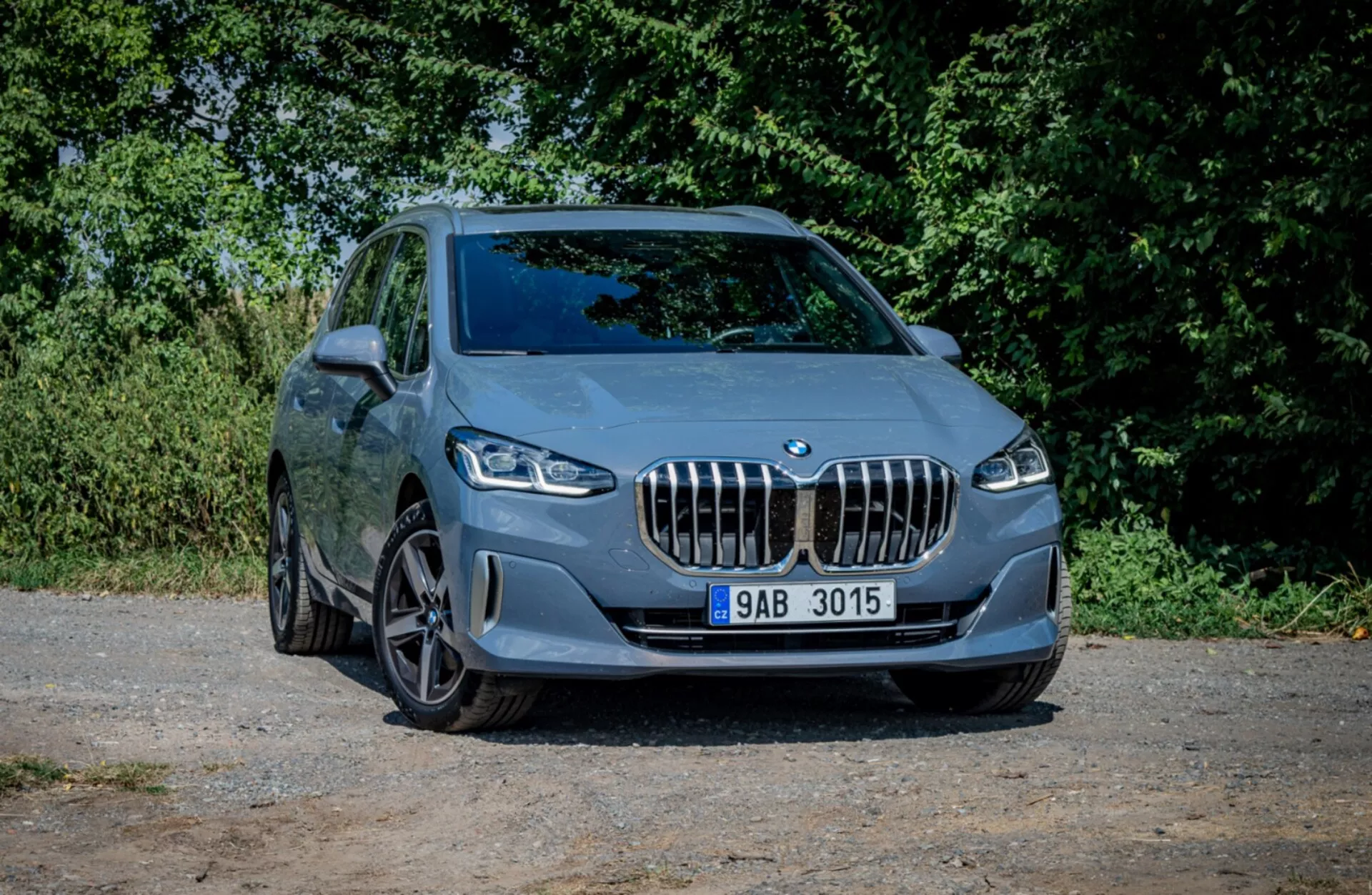 BMW serije 2 Active Tourer letnik 2022 parkiran na gramozu, ki prikazuje svojo športno zasnovo in sodobne lastnosti iz kota tri četrtine spredaj z naravnim ozadjem