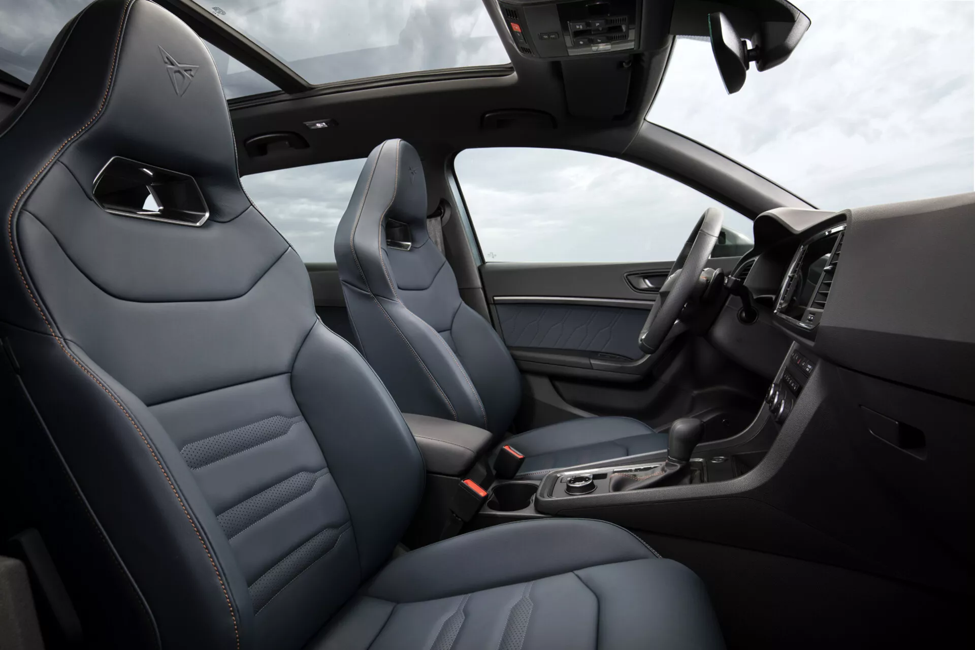 Notranjost Cupra Ateca 2020, ki prikazuje razkošne usnjene sedeže z diamantnim šivom, elegantno sredinsko konzolo z tehnološkimi funkcijami, digitalni zaslon armaturne plošče in del volana z gumbi, pod osvetljenim sončnim strešnim oknom