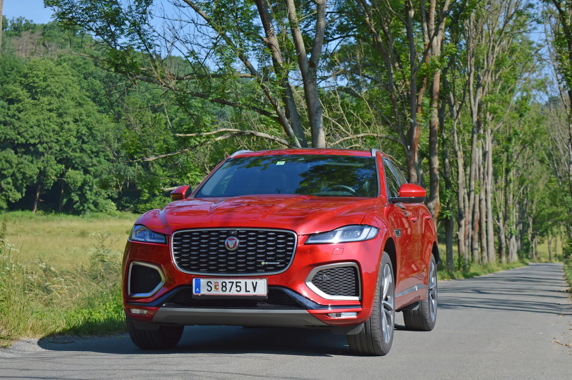 Luksuzni SUV Jaguar F-Pace 2021 v elegantni srebrni barvi, ujet v dinamični mestni vožnji, poudarja svojo značilno sprednjo masko, LED žaromete in športna lita platišča.