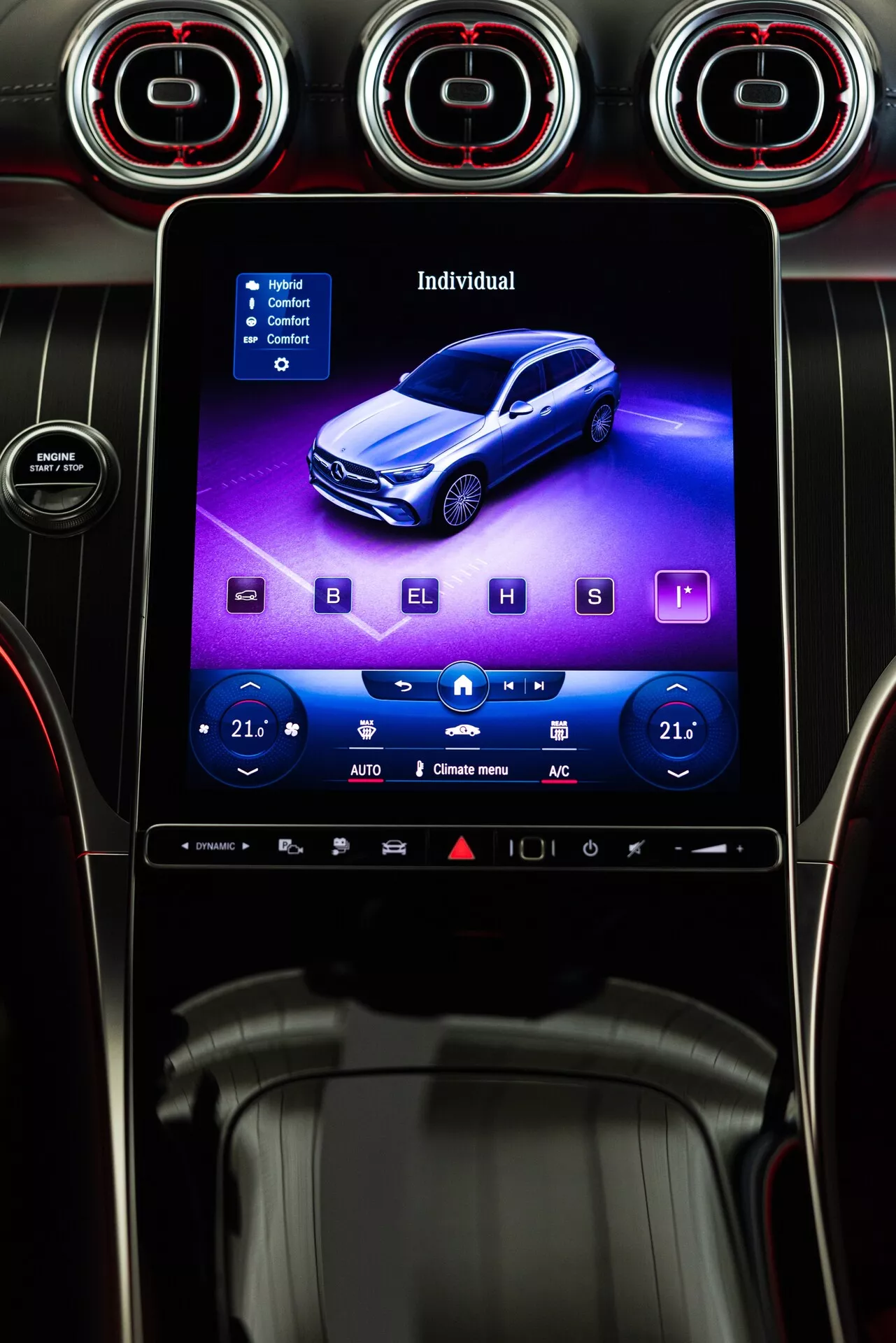 Digitalna ilustracija na infotainment zaslonu Mercedesa GLC 2022, prikazuje moder avto iz visokega 3/4 perspektive spredaj, obkrožen s fizičnimi kontrolami klimatskih naprav in tremi okroglimi zračniki z rdeče osvetljenimi obroči, v moderni in športni črni notranjosti s kovinskimi poudarki, gledano s sedeža voznika.