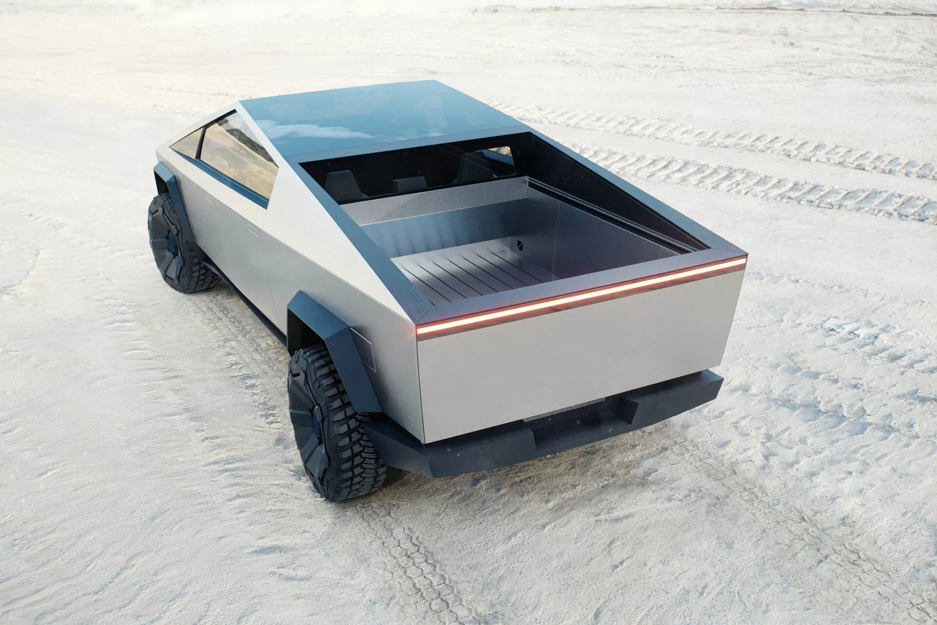 Futurističen in edinstven Tesla Cybertruck 2021, prva generacija, ujet z visokega zadnjega kota. Pogled vključuje zadnjo posteljo vozila, del njegovega bočnega profila in plosko streho. Zadnja postelja je plitva s plosko površino, obrobljena z neprekinjenim svetlobnim trakom, ki poudarja modern dizajn. Stranske plošče nimajo konvencionalnega oblikovanja, kar prikazuje minimalističen pristop. Velike terenske pnevmatike nakazujejo terenske zmogljivosti. Odsotnost tradicionalnih ogledal in izpušnih odprtin nakazuje na možno električno pogon. Tovornjak je postavljen na ravno, teksturirano površino, ki spominja na slano ploščo.