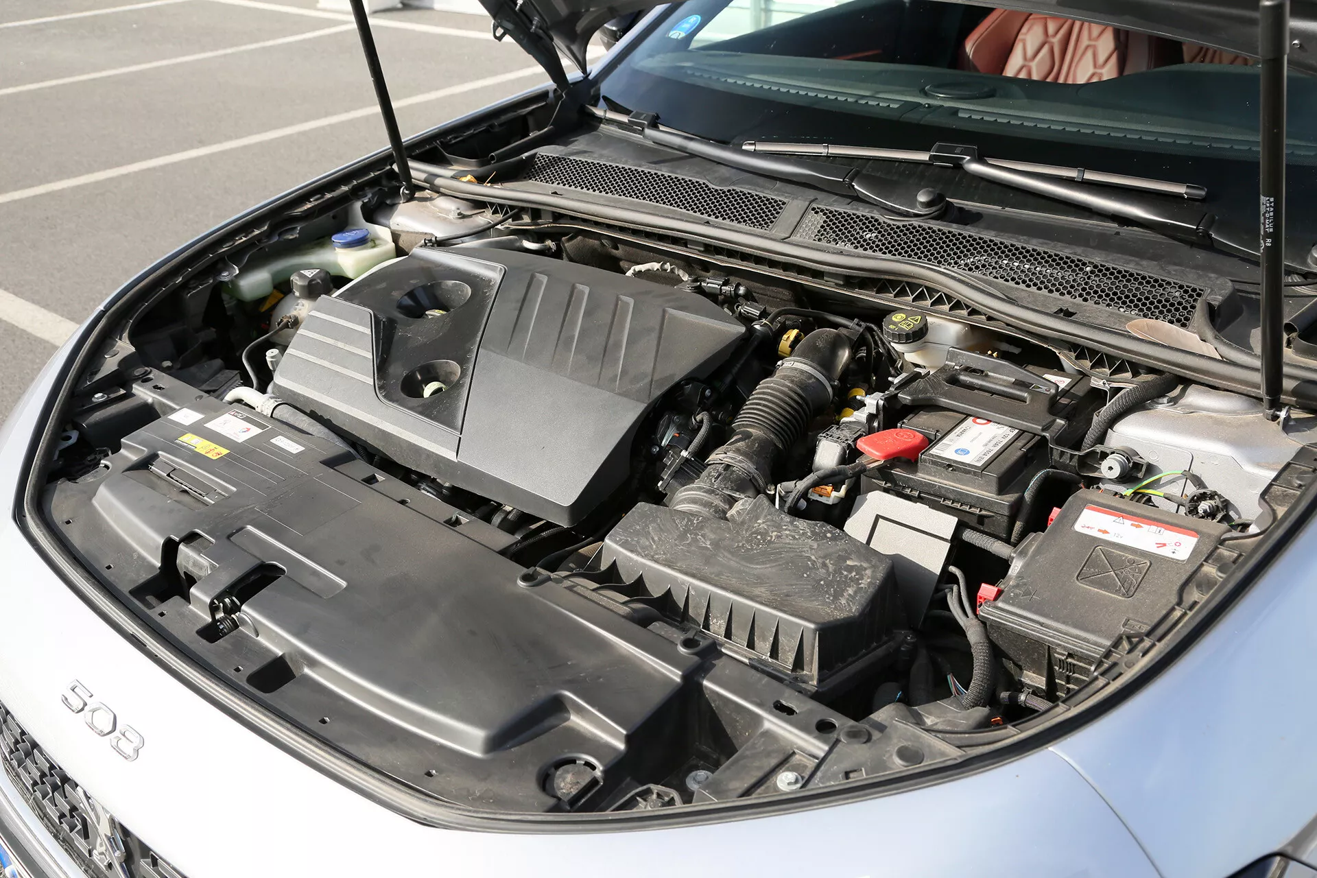 Podrobni pogled na odprt motorjski prostor Toyota Camry (Camry Limuzina) letnik 2001, ki prikazuje pokrov motorja z oznako '500', avtomobilsko baterijo, škatlo zračnega filtra, rezervoarje za tekočine, zapleteno kabelsko in cevno napeljavo, vidne komponente motorja pod pokrovom in radiator, kar poudarja sodobno tehnologijo motorja z notranjim izgorevanjem vozila.