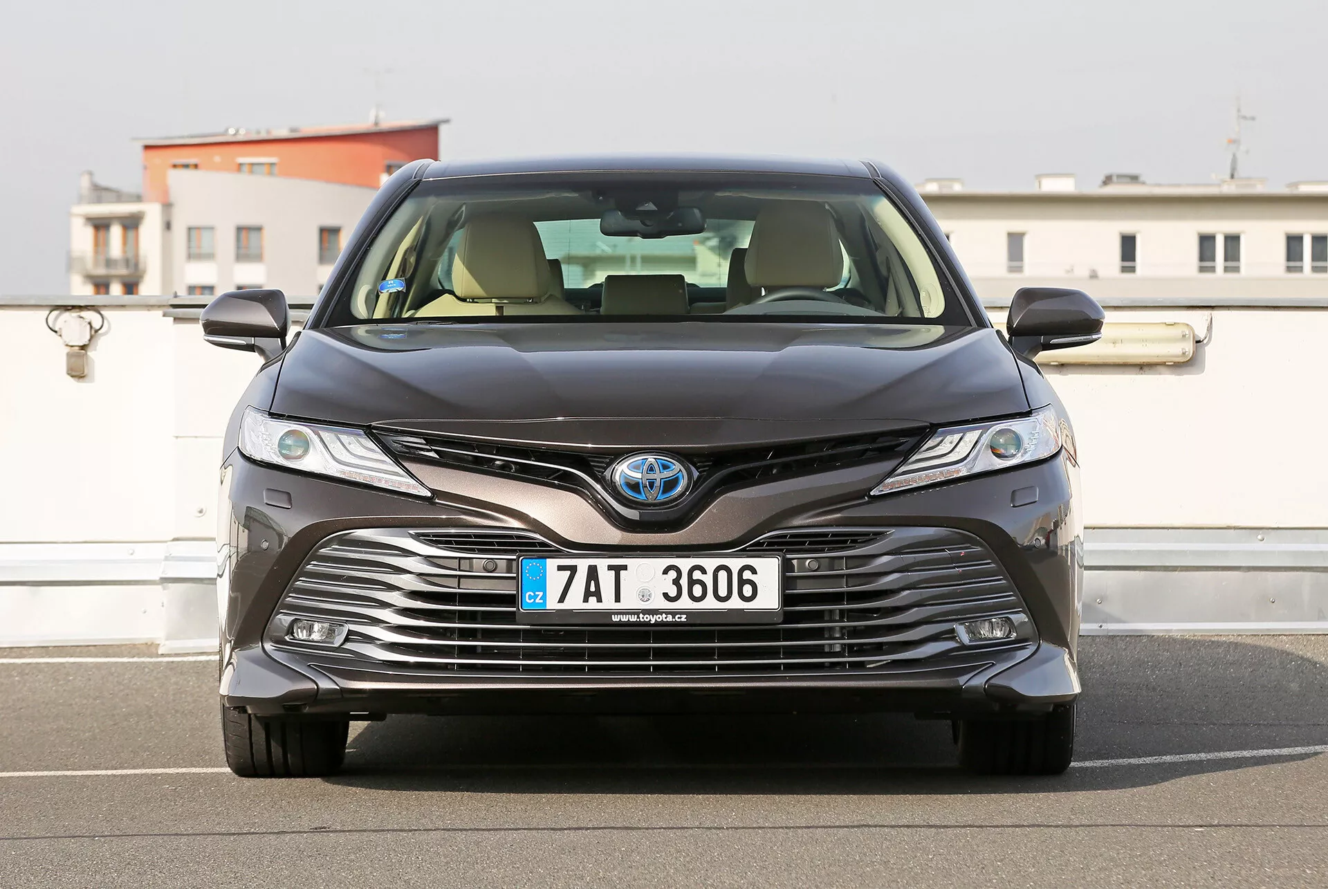Sprednji pogled na limuzino Toyota Camry 2001 z LED žarometi, kompleksna zasnova rešetke za aerodinamiko in hlajenje, postavljena proti urbanem ozadju z jasnim nebom