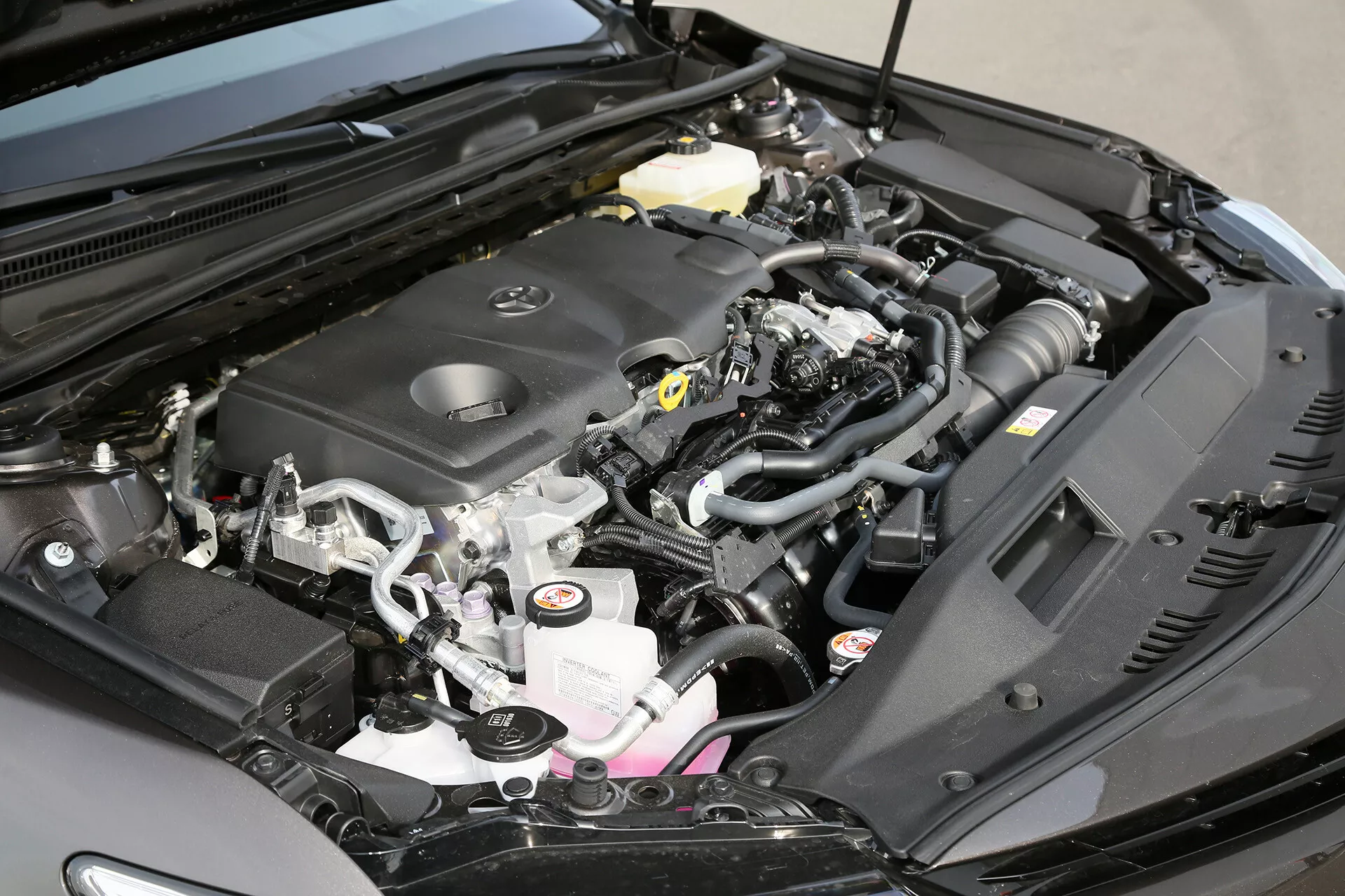 Podroben pogled na motorne predel Toyote Camry Limousine 2001 z prikazom pokrova motorja, sesalnega kolektorja, električnih povezav, posode za hladilno tekočino in zračne cevi