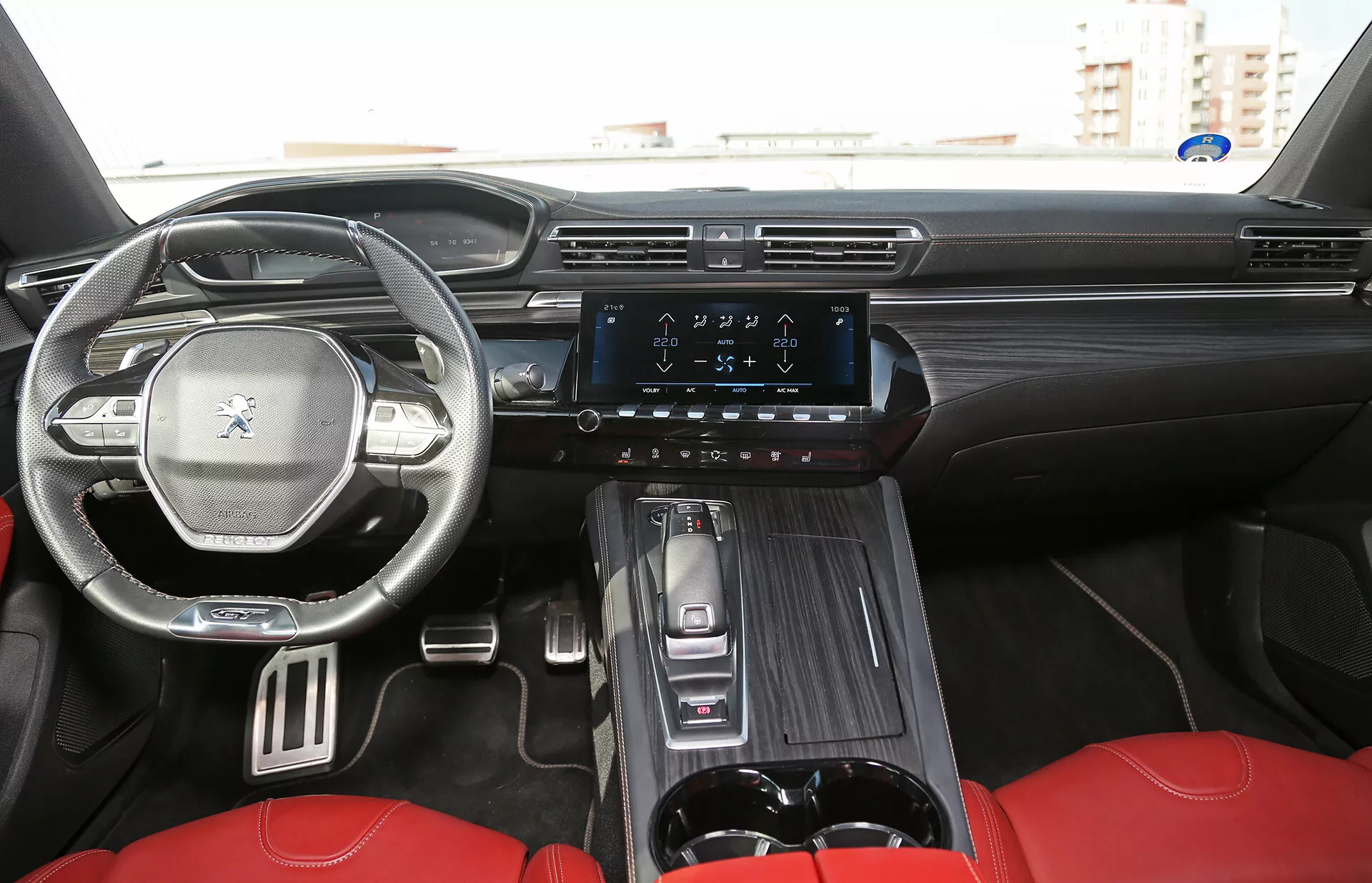 Notranji pogled na limuzino Toyota Camry 2001, osredotočen na sprednjo kabino z armaturno ploščo, volanom z nadzornimi gumbi, digitalnim prikazovalnikom, navpičnim zaslonom na dotik za infotainment sistem in luksuznimi rdečimi sedeži, kot je videno s zadnjega sedeža