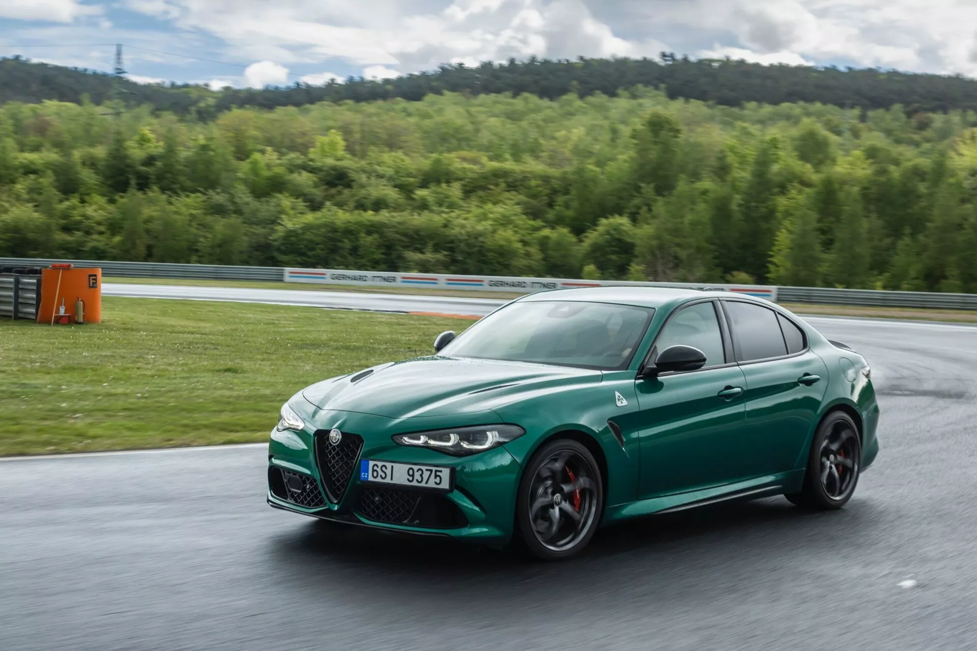 Alfa Romeo Giulia Quadrifoglio 2023 v gibanju, pogled z ​​sprednje četrtine prikazuje aerodinamično zasnovo, velike zračne vhode in športne zmogljivosti na dirkališču.