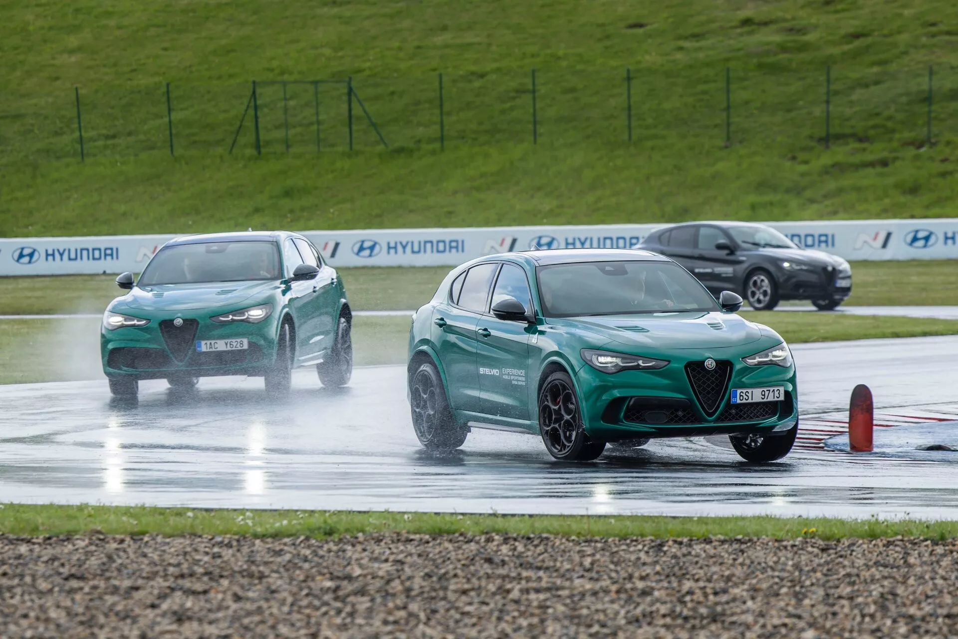 Alfa Romeo Giulia Quadrifoglio 2023 sodeluje v testu vožnje na mokrem, kaže športno zasnovo z vidno sprednjo rešetko, LED dnevnimi lučmi in lastnosti usmerjene k zmogljivosti proti ozadju škropljenja vode, ki ga povzroča gibanje