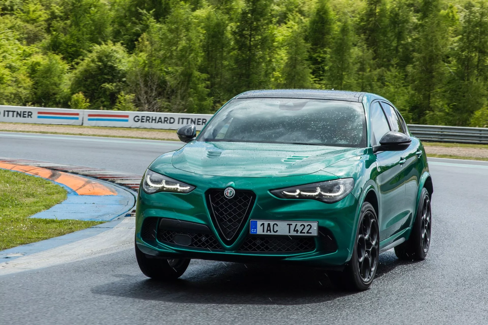 Alfa Romeo Giulia Quadrifoglio 2023 v vibrantni temno zeleni barvi, ki prikazuje svojo športno eleganco z vrhunskimi LED žarometi in na zmogljivost usmerjenim dizajnom na dirkališču, kar uteleša dinamiko modernega športnega sedana.