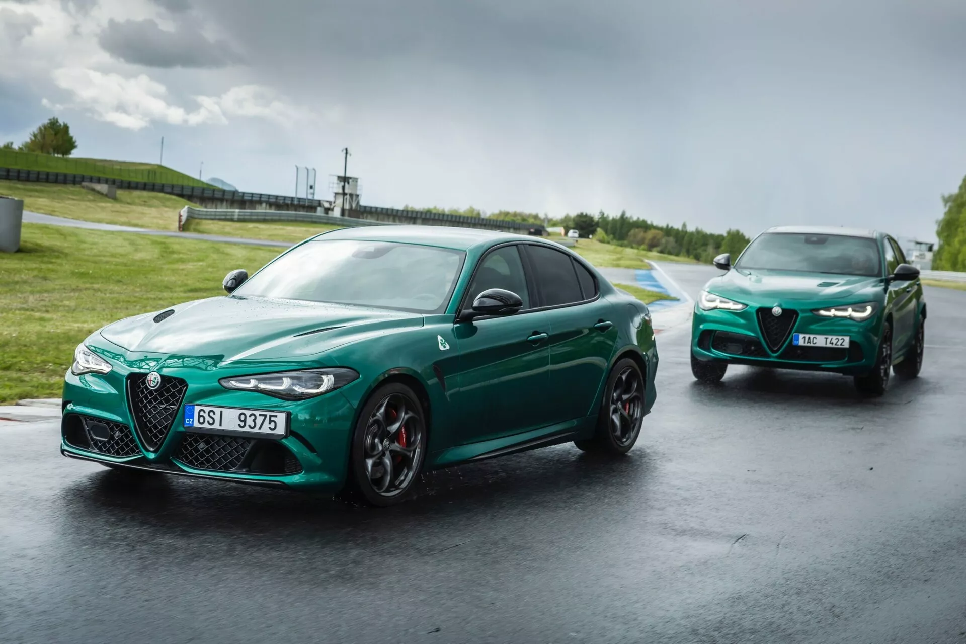 Alfa Romeo Giulia Quadrifoglio 2023 na mokri dirkaški stezi, kaže agresiven sprednji dizajn z rešetko Scudetto in vitkimi LED žarometi, v živahno zeleni barvi