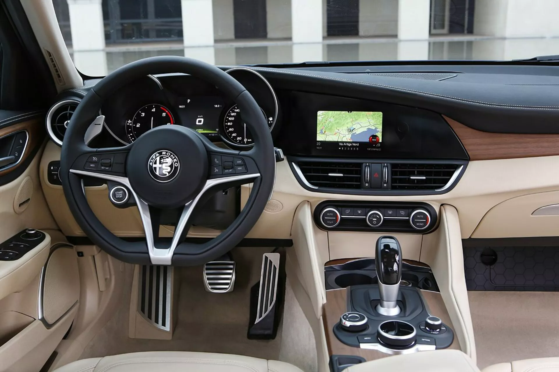 Notranjost Alfa Romeo Giulia 2016 s pogledom na voznikovo stran z usnjenim volanom, armaturno ploščo in sredinsko konzolo