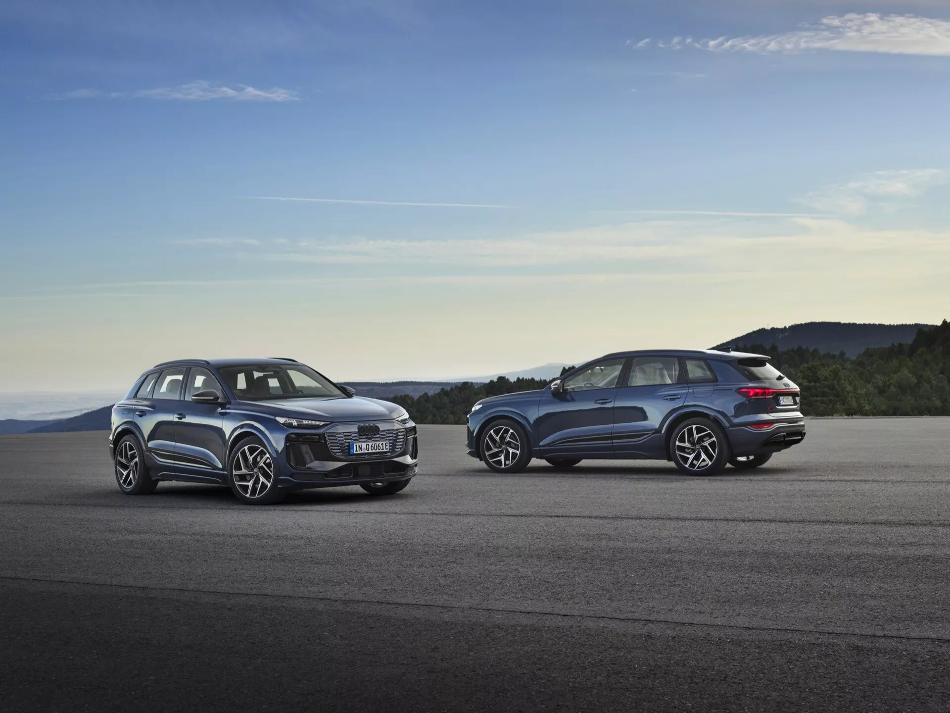 Audi Q6 e-tron 2024 (GF) parkiran ob sončnem zahodu, ki prikazuje svojo elegantno aerodinamično zasnovo, futuristične LED žaromete, prostorno notranjost, velika platišča in napreden električni pogon.