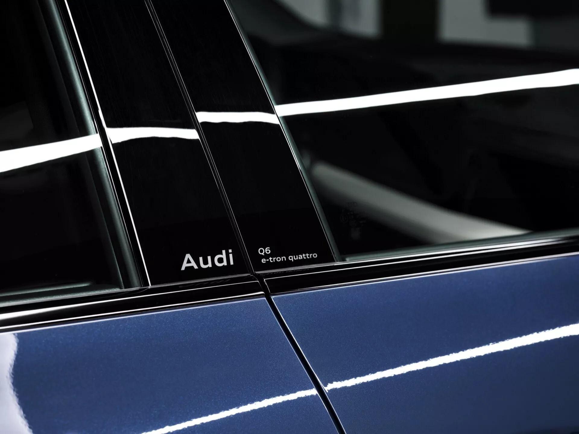 Visokoločljiv stranski profil 2024 Audi Q6-e-tron quattro v globoko modri barvi z sijočim zaključkom, ki prikazuje poudarjene znamke in podrobne oblikovalske značilnosti, poudarja B-stebriček med vrati in odsevno osvetlitev.