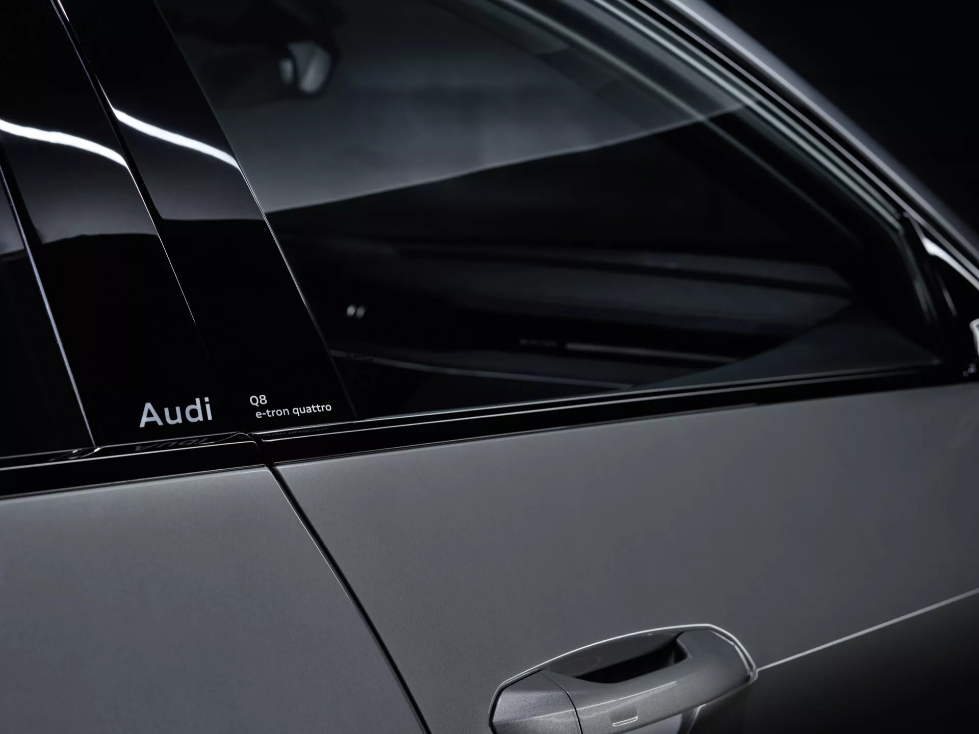 Podrobnost bočnega profila Audi Q8-e-tron 2023, ki prikazuje značko Quattro, C-stebriček in zadnje okno za potnike, poudarja obliko vozila in sistem pogona na vsa kolesa