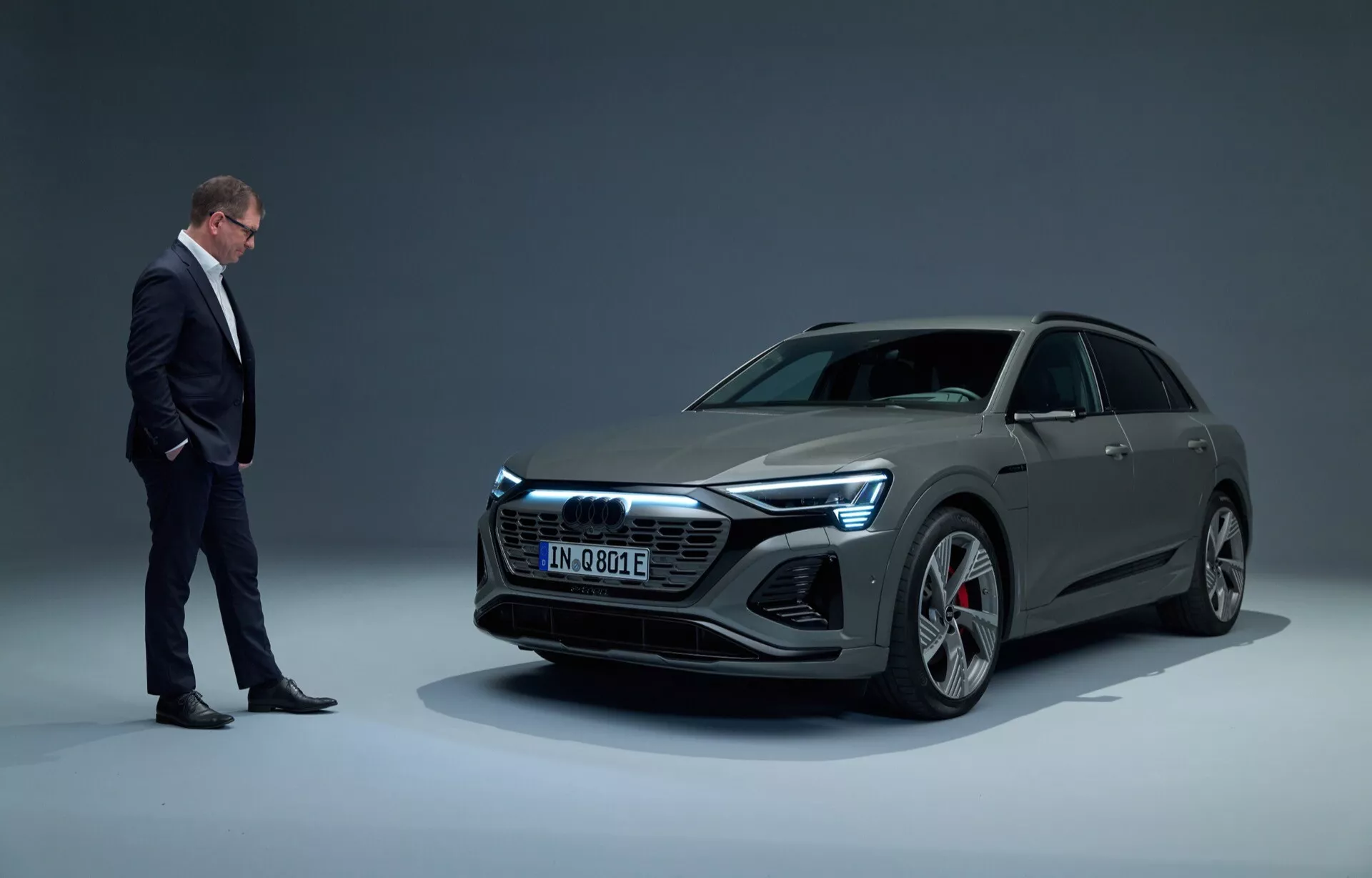 Audi Q8 e-tron 2023 v studijskem okolju, prikazuje sodobno električno luksuzno vozilo z elegantno zasnovo, vidno iz nizkega kota tridelni pogled od spredaj proti gradientnemu ozadju, z LED žarometi in velikimi platišči iz zlitine