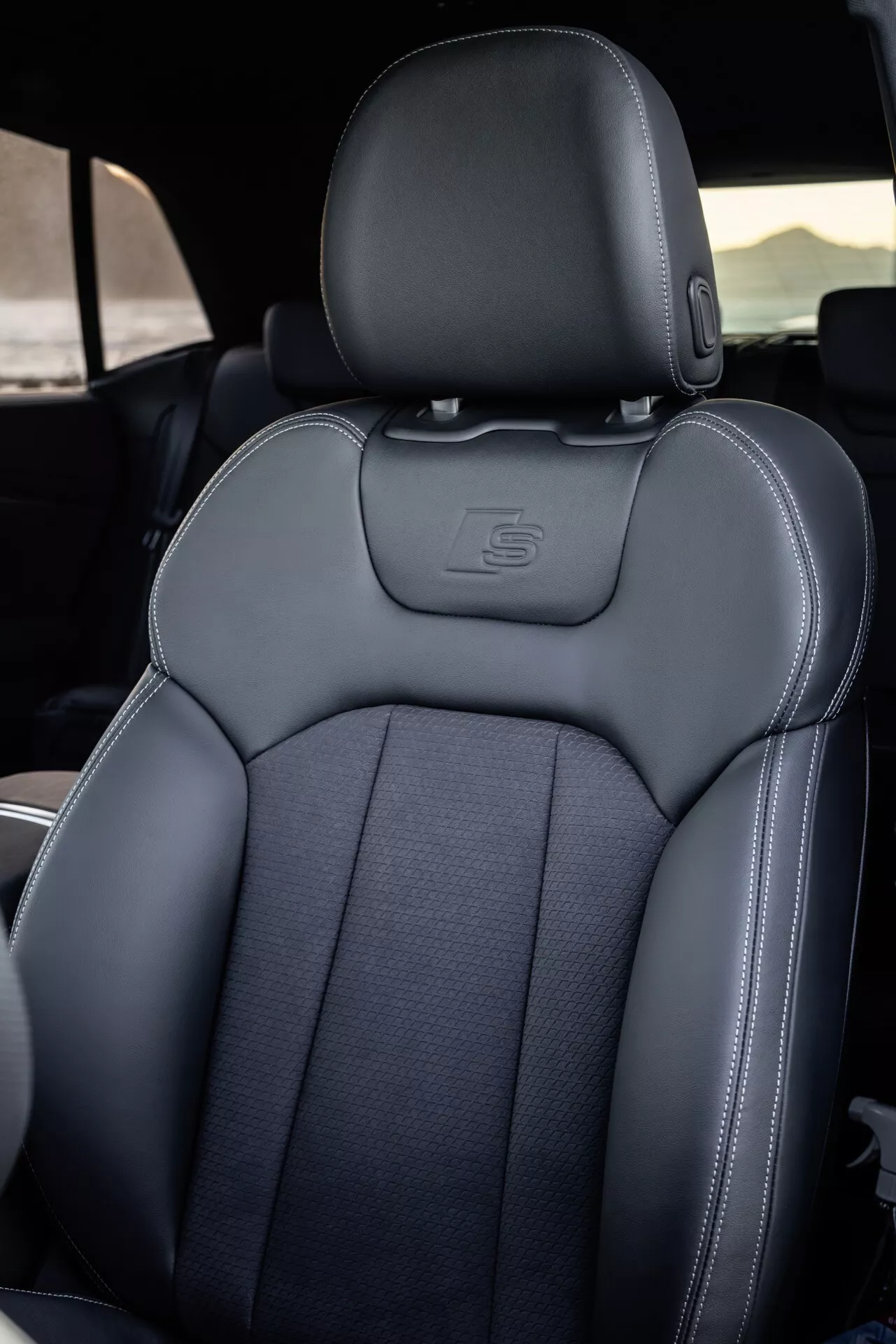 Notranjost Audi Q8 (4M-Facelift) 2023 s poudarkom na voznikovem sedežu z detajlnim šivanjem, luksuznimi materiali in športno ergonomijo, delno vidnim volanom, ki označuje stran voznika