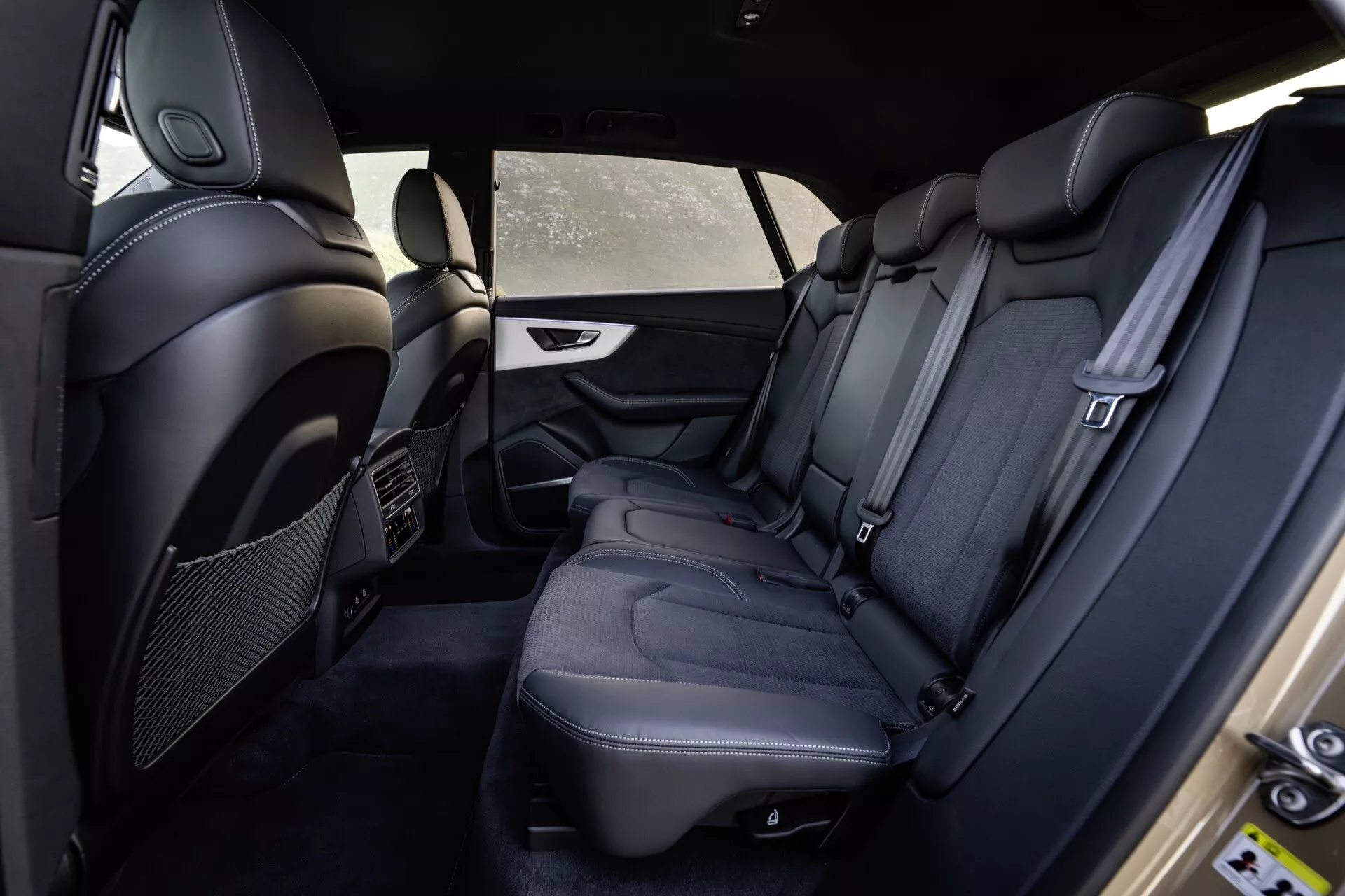 Notranjost Audi Q8 4M-Facelift 2023, ki prikazuje zadnji potniški prostor s strani voznika z vrhunskimi črnimi usnjenimi sedeži, podrobnimi šivi, luksuznimi dodatki in varnostnimi funkcijami