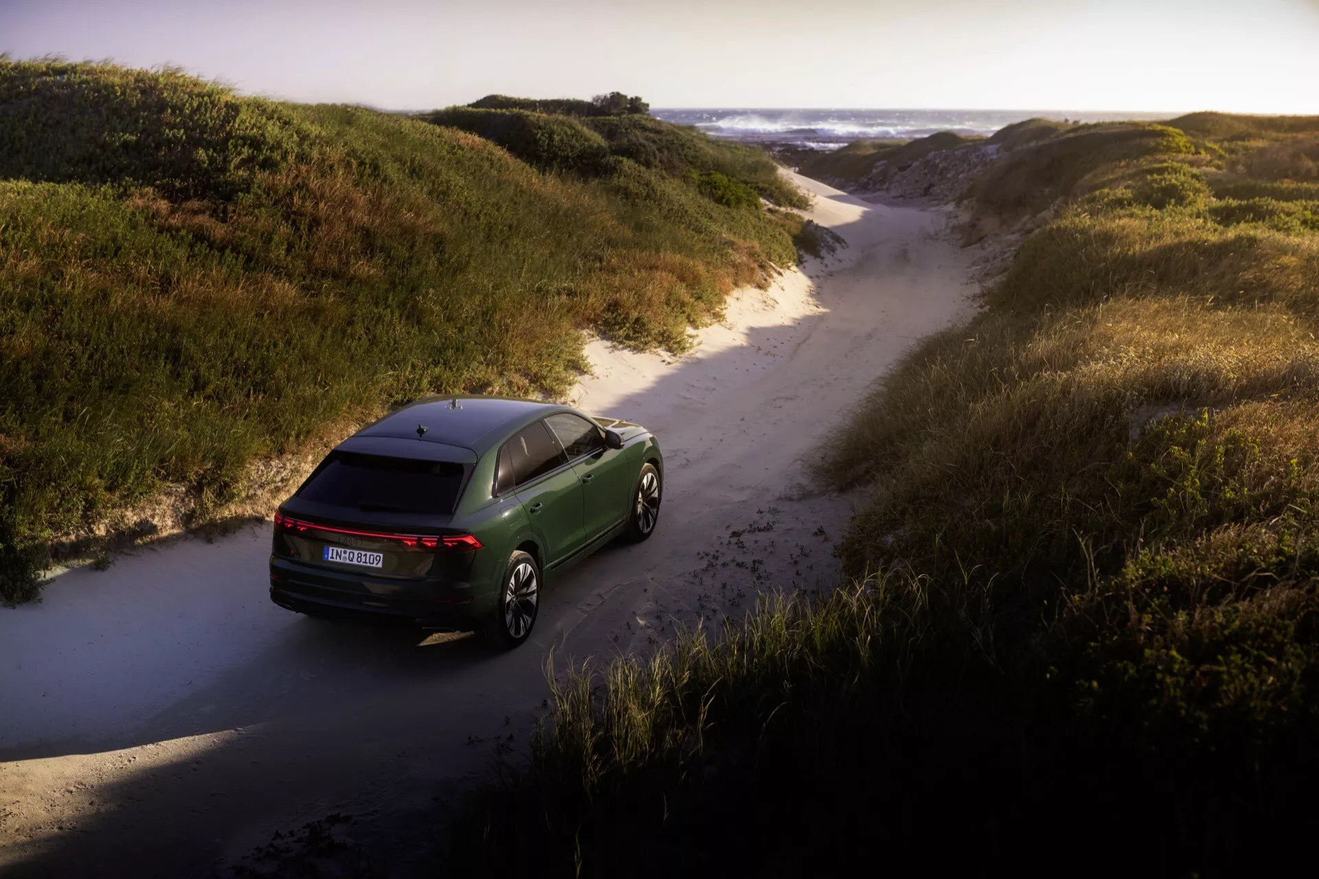 Audi Q8 2023 (4M-Facelift) posnet iz ptičje perspektive, ki prikazuje aerodinamično obliko, LED zadnje luči in premium lita platišča v naravnem terenskem okolju