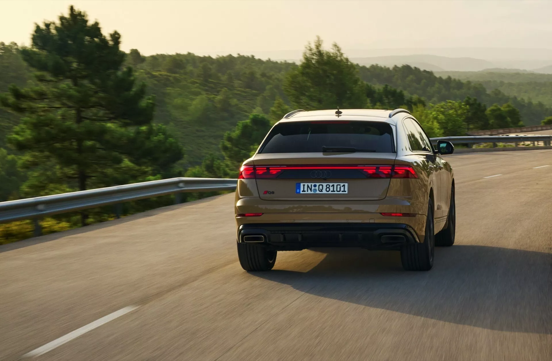 Audi Q8 2023 (4M-Facelift) je prikazan v dinamični zadnji četrtinski pogledi med vožnjo po odprti cesti, kar prikazuje njegov celotni oblik zadnje svetilke in dvojne izpušne nasvete