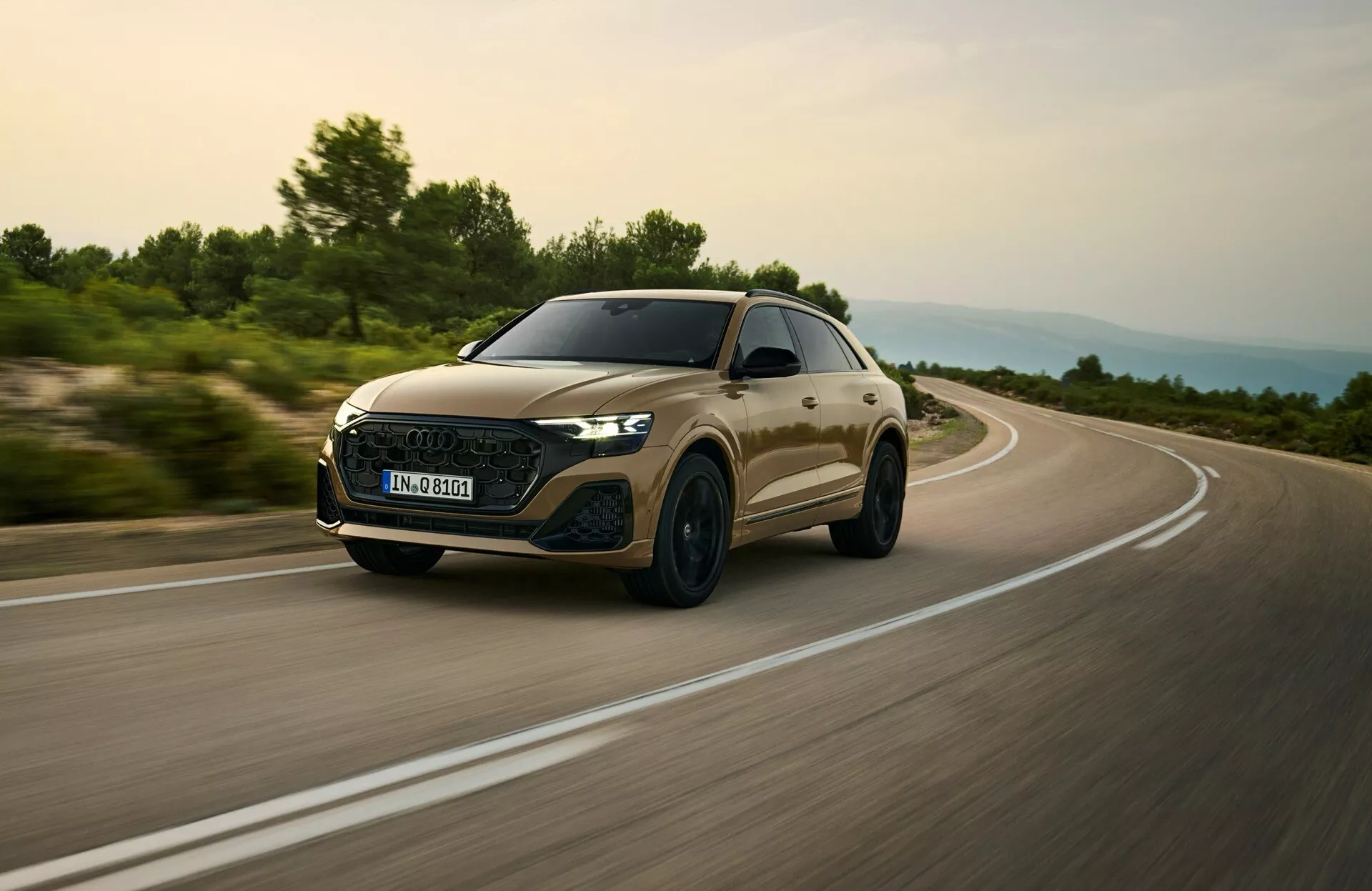 Audi Q8 2023 (model 4M facelift) ujet v dinamični vožnji, osredotočen na njegov aerodinamični sprednji žar, LED žaromete in eleganten profil iz nizkega kotnega pogleda tri četrtine spredaj, kar nakazuje hitrost in premium lastnosti