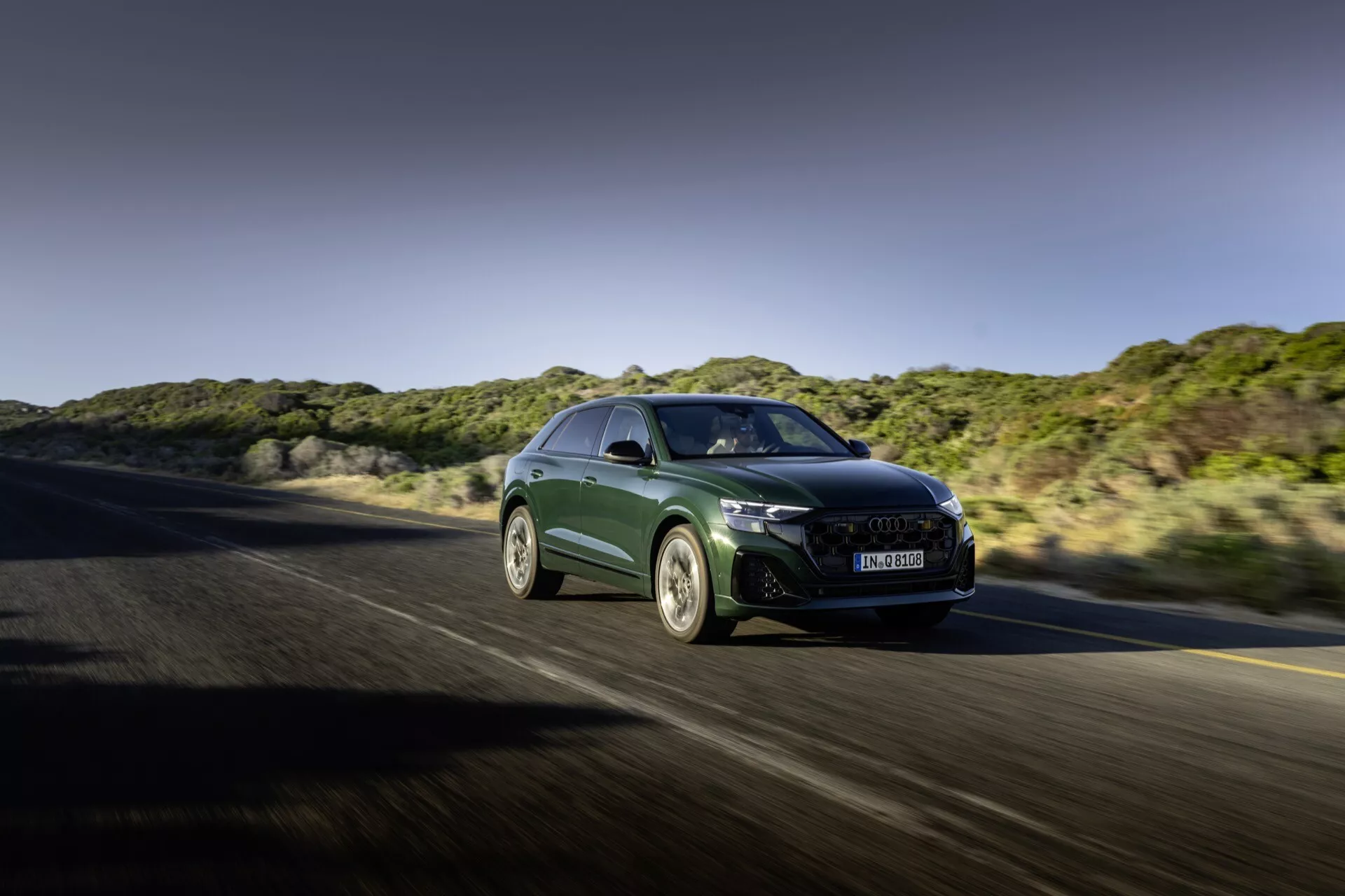 Audi Q8 2023 (4M-Facelift) v gibanju, prikazuje aerodinamično obliko, ostre LED žaromete, veliko masko z naprednim hlajenjem, športna lita platišča in značilnosti visoke zmogljivosti z vidika sprednje tričetrtine na avtocesti