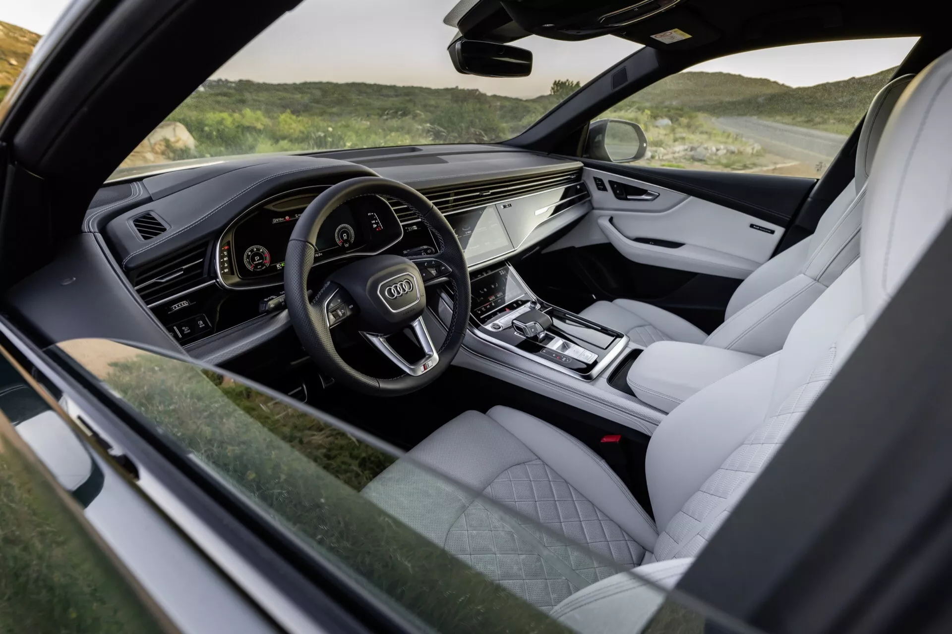 Pogled na notranjost Audi Q8 2023 (4M-Facelift), ki poudari pilotsko kabino na strani voznika z digitalnim instrumentalnim sklopom, občutljivim sistemom za informacije in zabavo ter razkošnimi zaključki, kot so usnjena oblazinjenja in kovinski poudarki