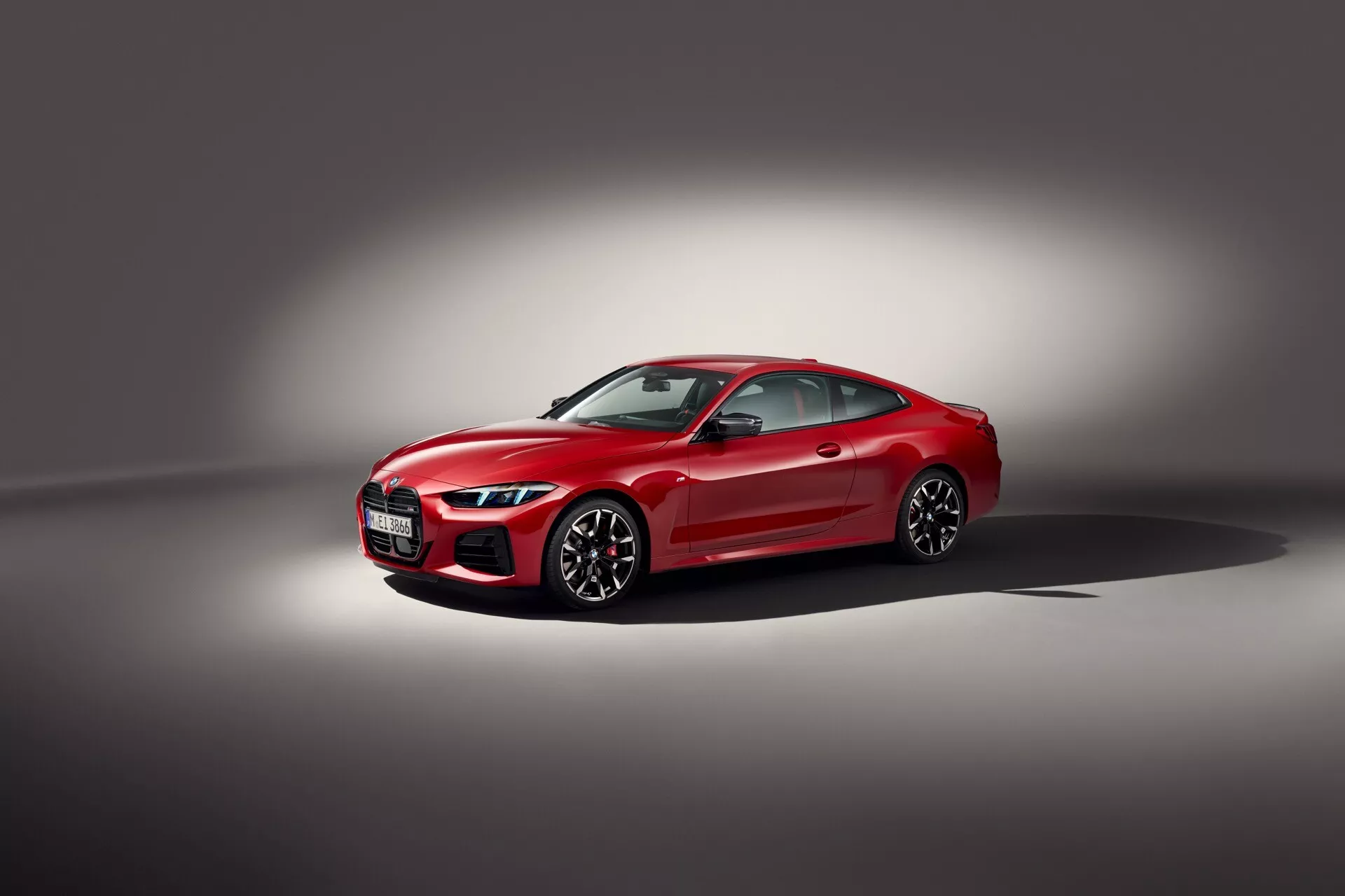Kupe BMW serije 4 letnik 2024 (G22-G23-G26-G82-G83 Facelift) v rdeči barvi, prikazuje športno sprednjo rešetko z emblemo, ozke kotne LED žaromete, aerodinamična stranska ogledala, rahlo zatemnjena okna, večkraka lita platišča z visoko zmogljivimi zavorami, v studijskem okolju s svetlobnim žarometom, ki poudarja razkošne in napredne tehnološke lastnosti