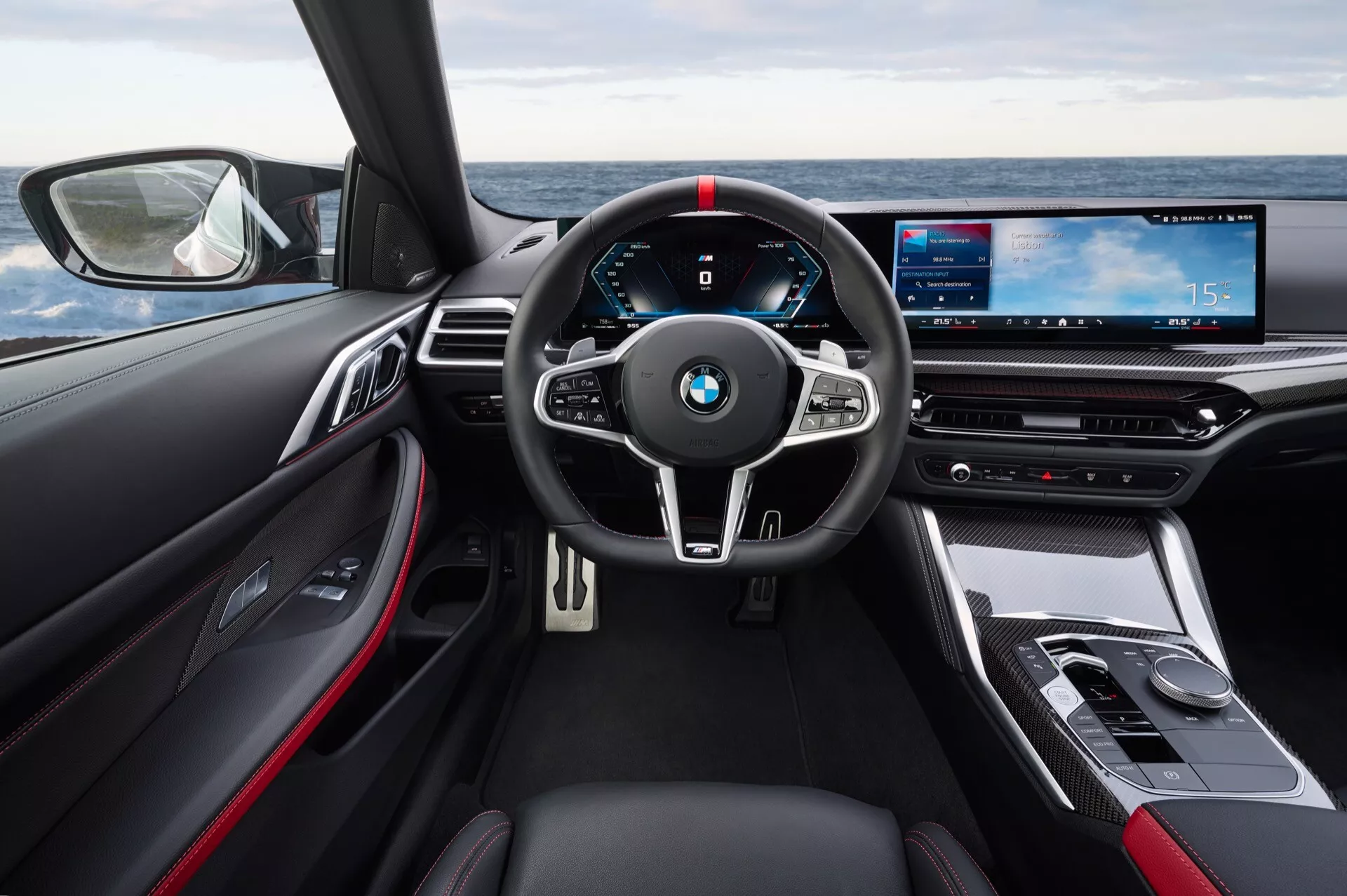 Notranjost BMW serije 4 letnik 2024 (G22-G23-G26-G82-G83 prenova) s poudarkom na volanu in digitalni armaturni plošči z vidika voznikovega sedišča, ki prikazuje napredno tehnologijo in luksuzne lastnosti