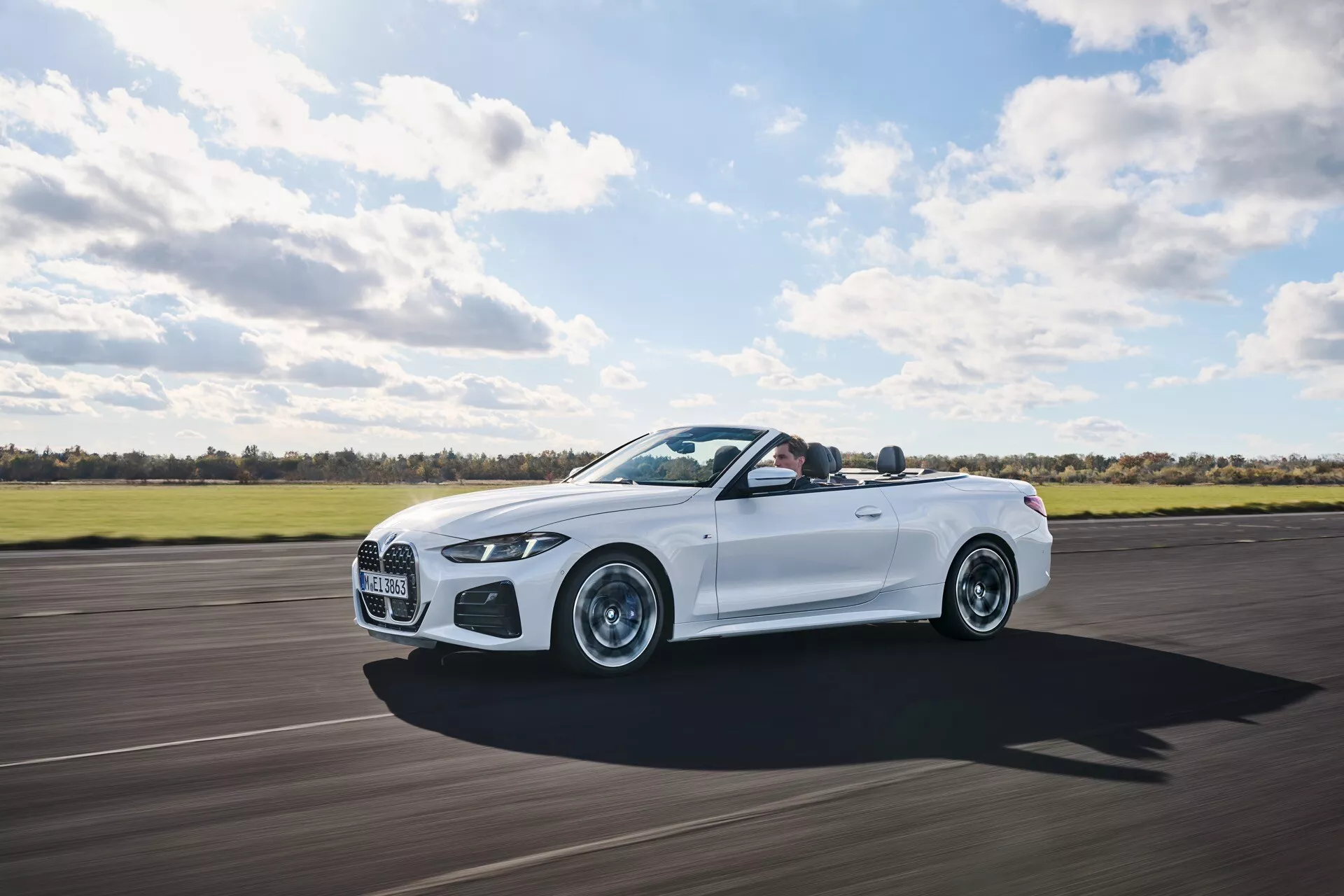 Kabriolet BMW serije 4 2024 (preoblikovanje G22-G23-G26-G82-G83) v gibanju, ki prikazuje luksuz z odprto streho, dinamične linije oblike in visoko zmogljivostne lastnosti