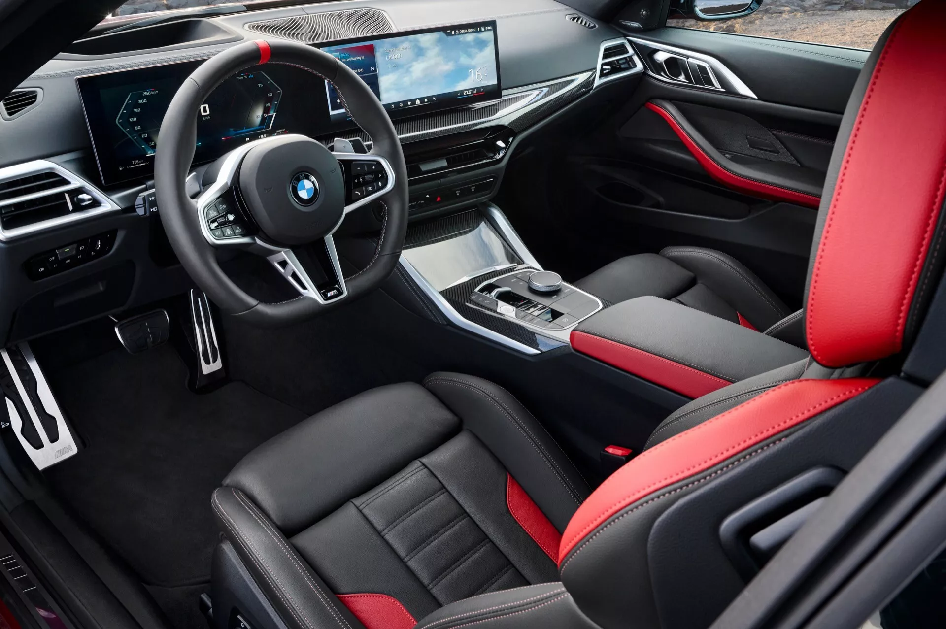 Notranjost BMW serije 4 (G22-G23-G26-G82-G83 Facelift) za leto 2024 iz perspektive voznikove strani, ki prikazuje športne sedeže iz črnega usnja z rdečimi poudarki, multifunkcionalni volan, elegantno armaturno ploščo z digitalnimi zasloni in sofisticirano sredinsko konzolo
