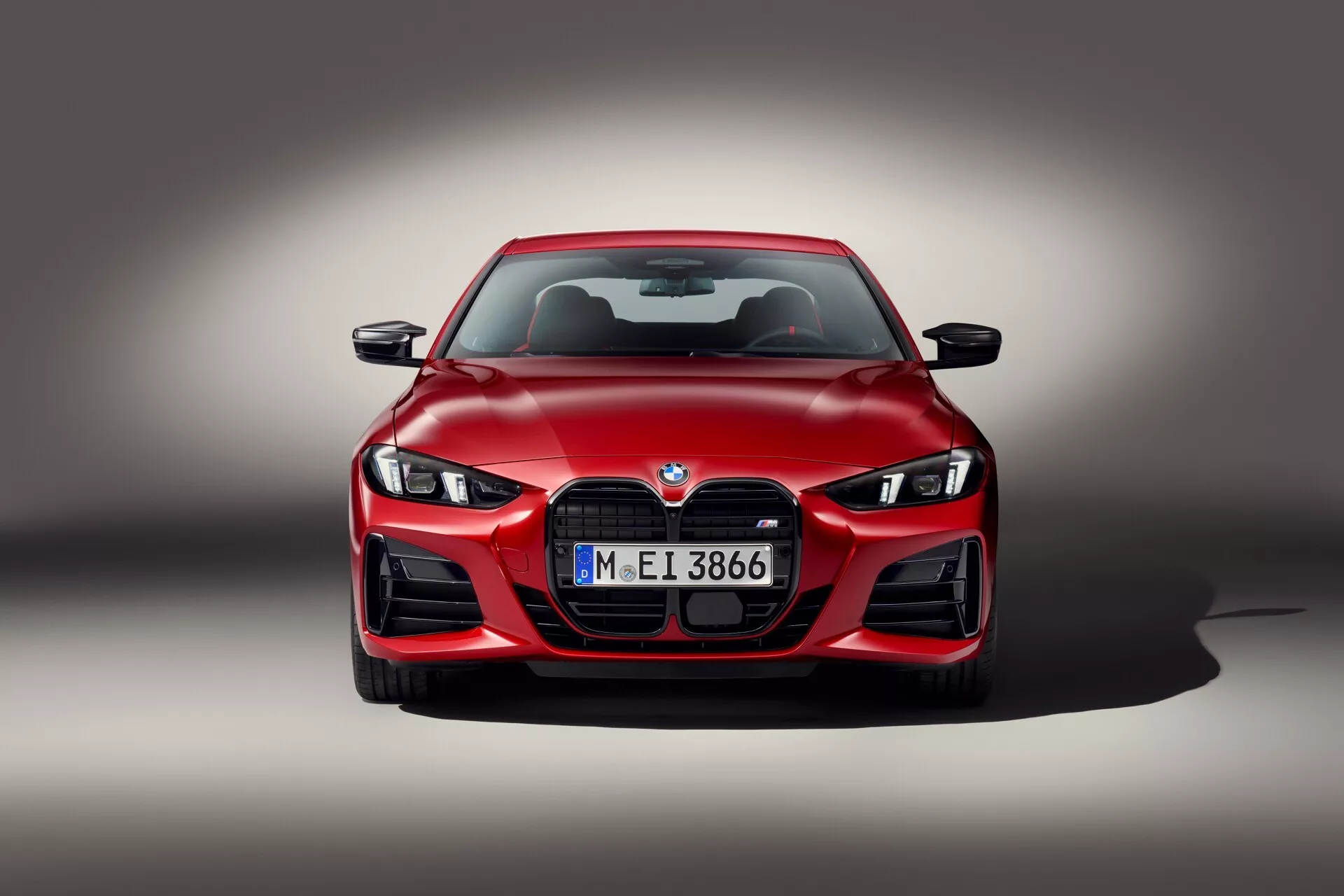 Sprednji pogled na BMW serije 4 2024 (G22-G23-G26-G82-G83 Facelift) z LED žarometi, veliko ledvično masko in aerodinamičnim dizajnom na gradientno sivi ozadju