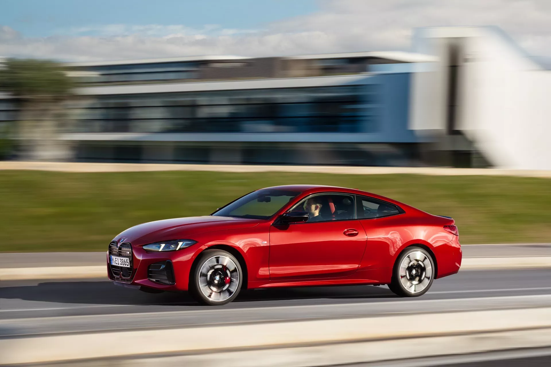 Rdeč športni kupe BMW serije 4 (G22-G23-G26-G82-G83 Facelift) v gibanju, stranski pogled s tehniko zajemanja gibanja, ki prikazuje aerodinamično zasnovo, LED dnevne luči in zmogljive velike zračne vhode.