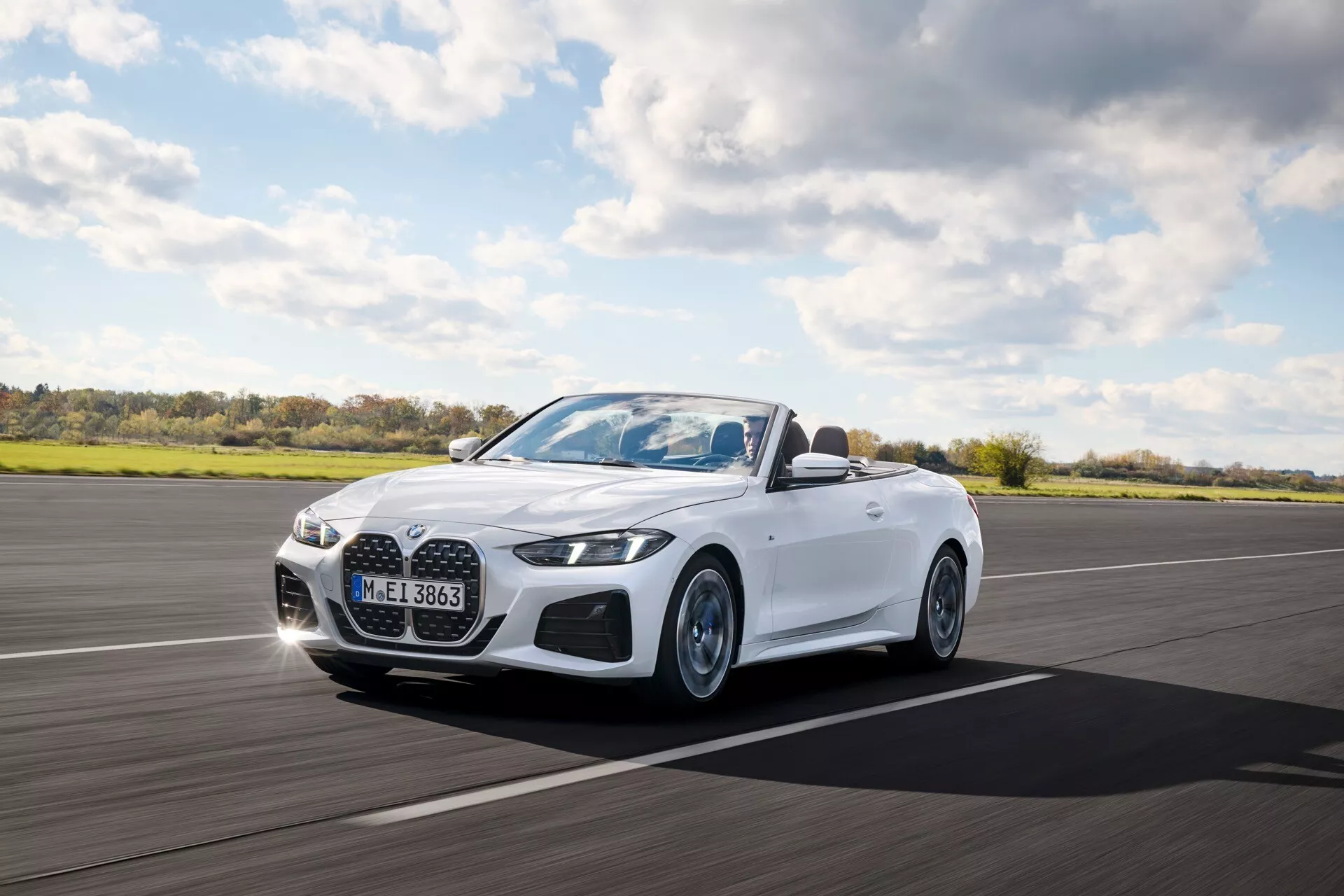 BMW serije 4 kabriolet (G22-G23-G26-G82-G83 Facelift) letnik 2024 v gibanju, predstavlja LED žaromete, izrazit sprednji žar in belo zunanjo podobo iz perspektive spredaj tri četrtine