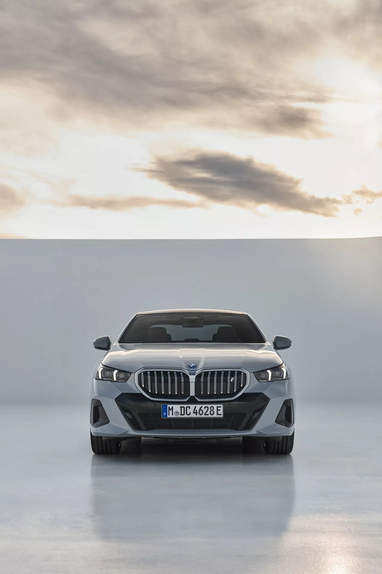 Sprednji pogled na BMW serije 5 (G60-G61) za leto 2023, ki prikazuje dvojno ledvičko, LED žaromete z dnevnimi lučmi, konturirane linije pokrova, emblem proizvajalca, zmogljiv sprednji odbijač z velikimi zračnimi vstopi, morebitni integrirani senzorji za pomoč vozniku, in poliran zaključek proti čistemu studijskemu ozadju