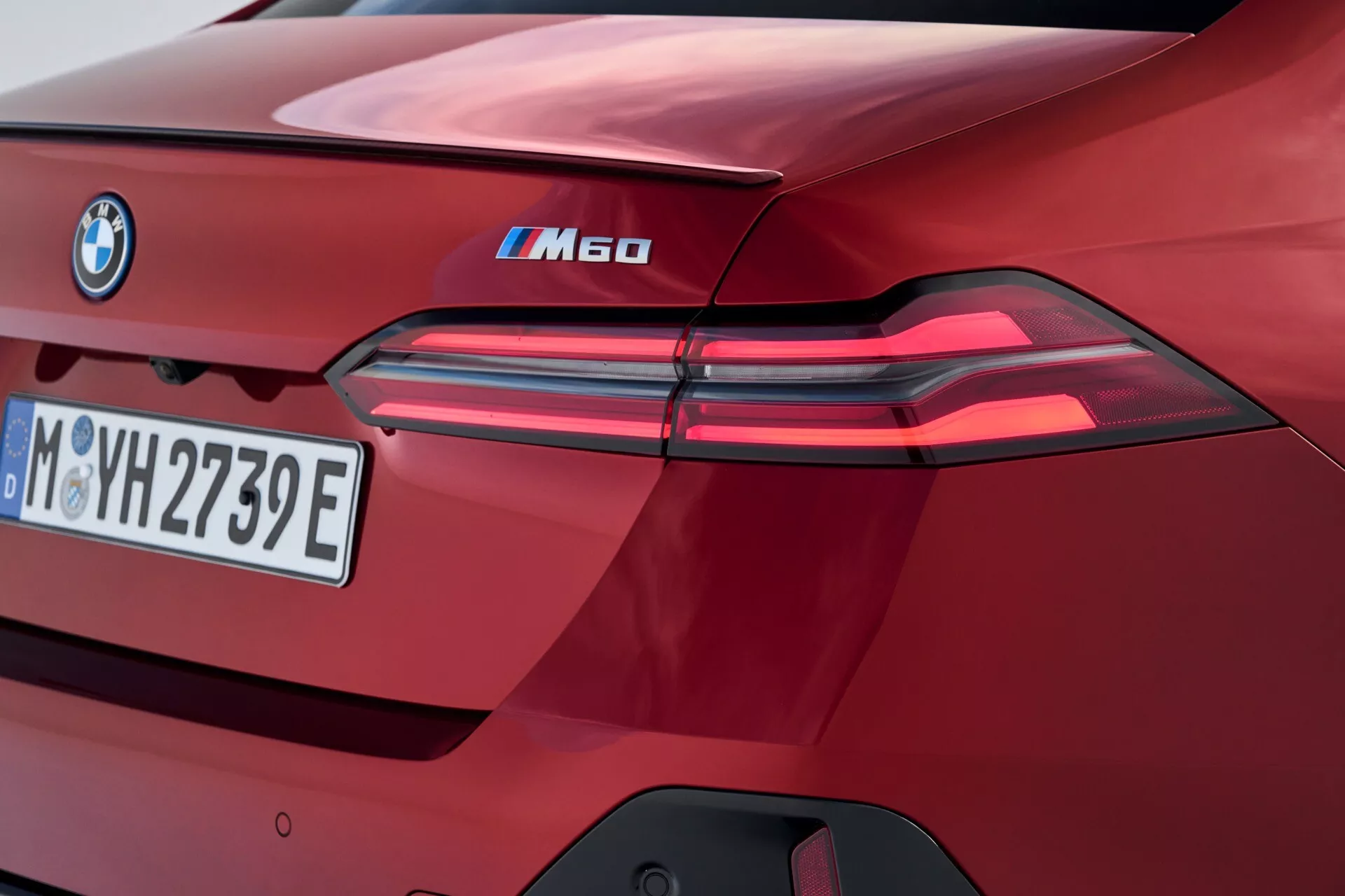 Pogled od blizu na zadnji del BMW serije 5 iM60 letnik 2023, poudarjajoč LED zadnje luči, značko iPerformance, evropsko registrsko tablico, visok sijaj bordo barve, in značilne oblikovalske elemente