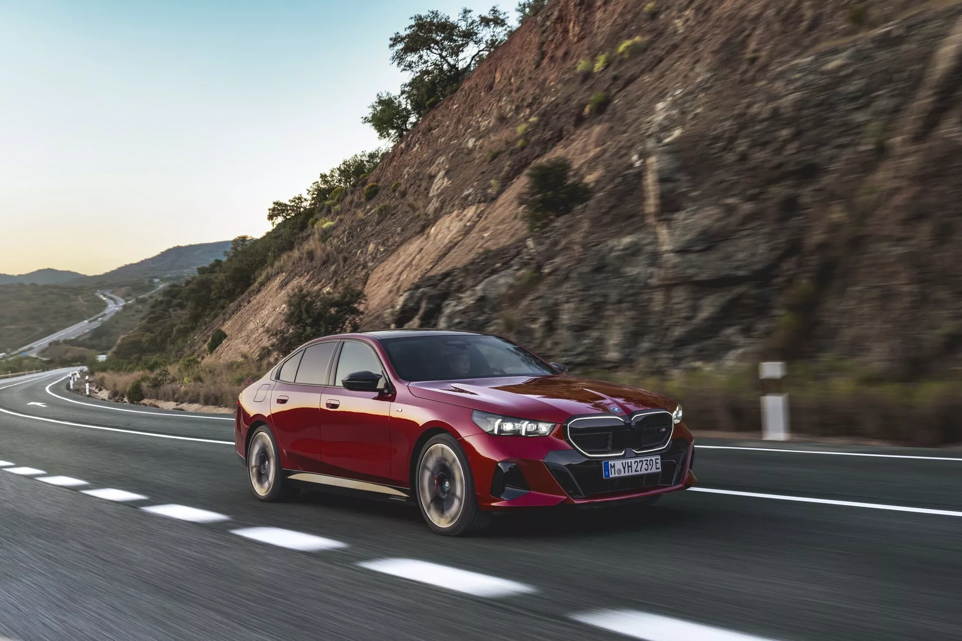 Sedan BMW serije 5 (G60-G61) letnik 2023 v gibanju, ki prikazuje dinamične vozne sposobnosti s poudarkom na naprednih avtomobilskih tehnologijah, LED žarometih in aerodinamičnem dizajnu pod nežno sončno svetlobo.