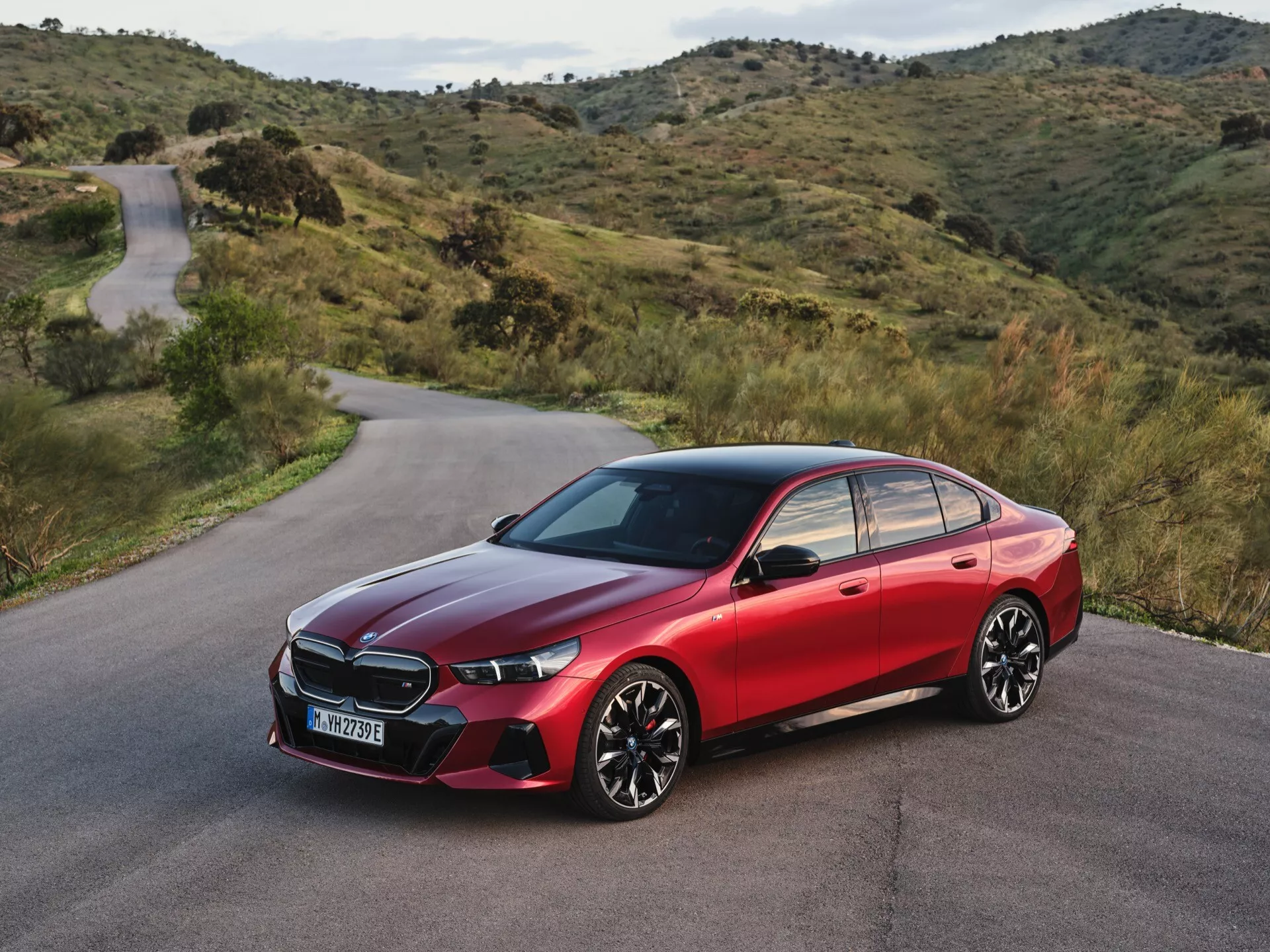 Sodobna limuzina BMW serije 5 (G60-G61) 2023 z oblikovanimi linijami, LED žarometi in športnim profilom na hriboviti cesti, ki poudarja razkošje in napredno tehnologijo