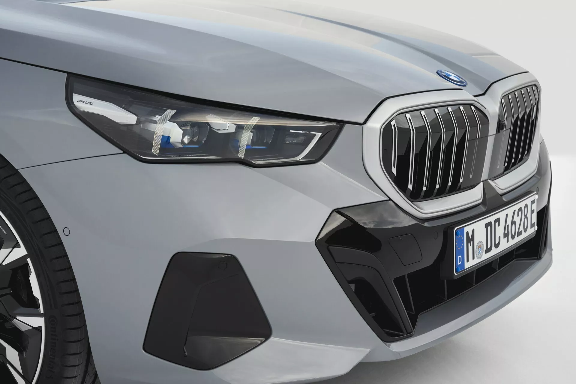 Pogled spredaj levo na BMW serije 5 (G60-G61) letnik 2023 s prikazovanjem LED žarometov, značilne ledvične maske, športnega sprednjega odbijača z zračniki, konturirane pokrova motorja, širokih blatnikov in kovinskega zaključka