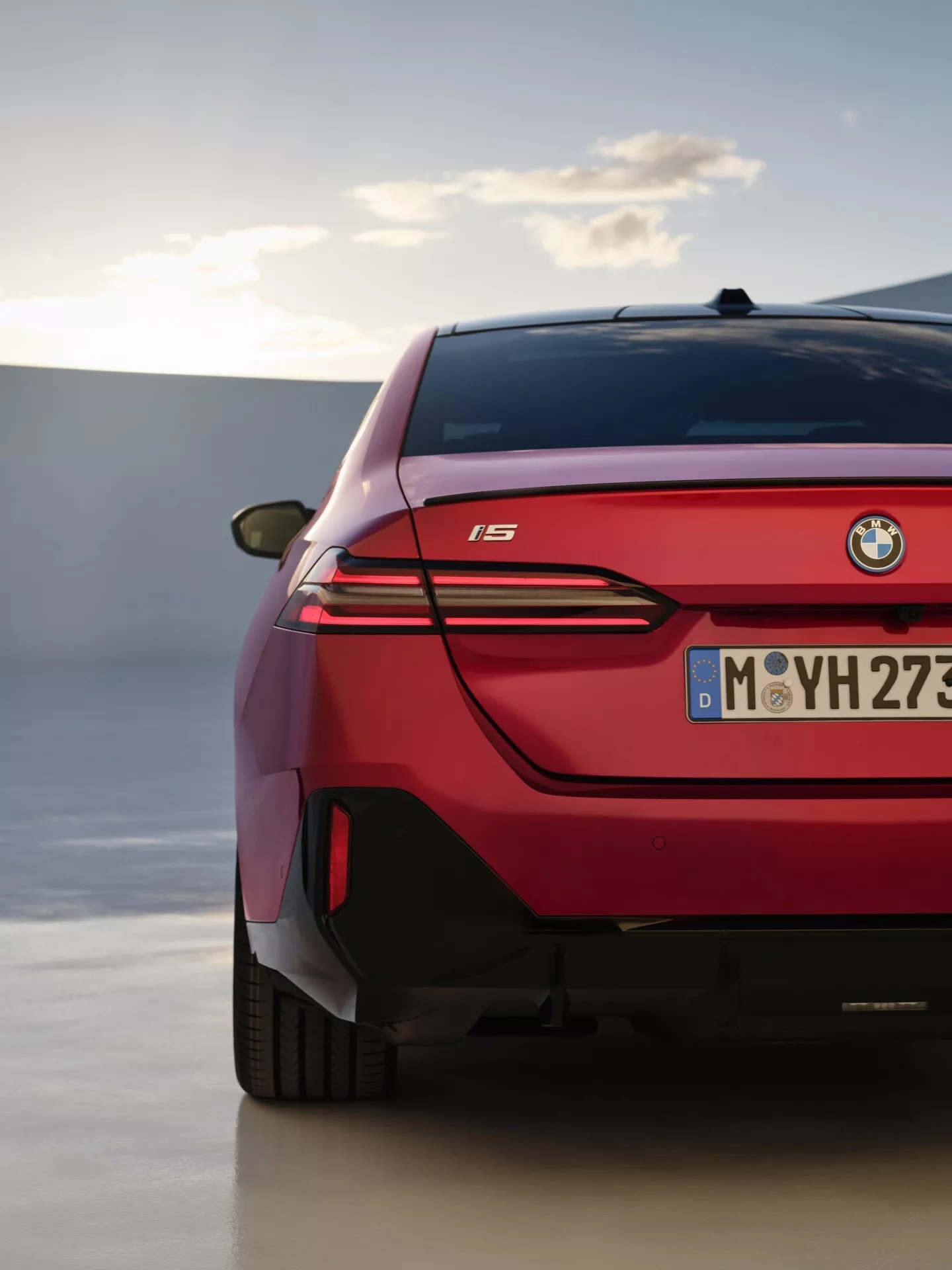Podroben pogled na zadnji del BMW serije 5 2023 (G60-G61), ki prikazuje LED zadnje luči, elegantno oblikovanje in emblemo modela 'i5' proti ozadju sofisticiranega zunanje prostora