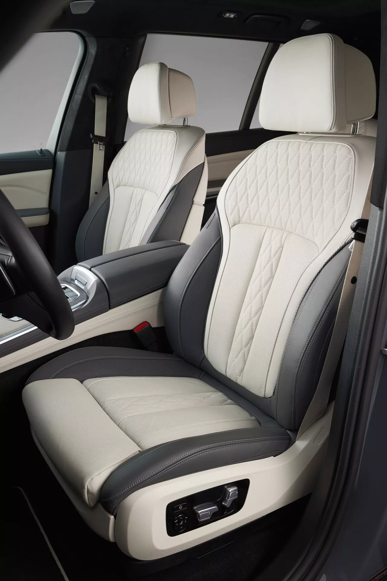 Podroben pogled na notranjost BMW X7 2022 (G07-facelift), osredotočen na premium dvobarvni usnjeni sedež za sovoznika z vzorcem prešitja v obliki diamanta, elektronske prilagoditve, ujemajoče se z luksuzno zasnovo vrat in sredinske konzole