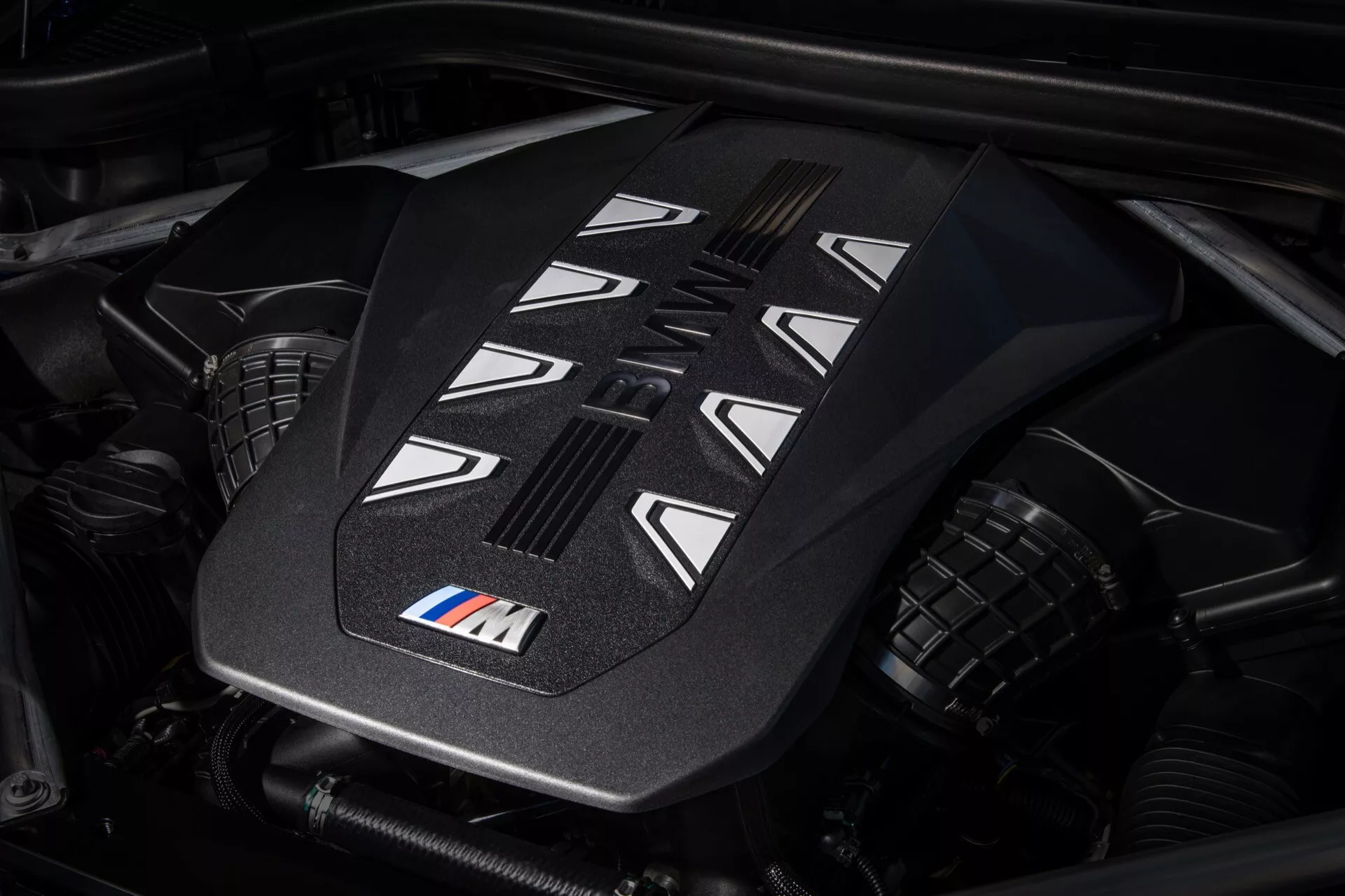 Od blizu pogled na pokrov motorja visoke zmogljivosti v BMW X7 2022 (G07-Facelift) z oznako M, ki prikazuje napredne oblikovalske lastnosti in reže za hlajenje