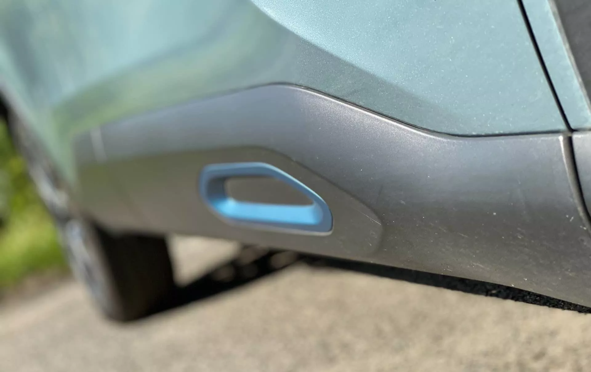 Bližnji posnetek stranskega detajla Citroen C4 2020 (e-C4), ki poudarja sodobno, aerodinamično integrirano kljuko vrat. Kljuka je izenačena s ploščo vrat in morda osvetljena za brezključni vstop, kar nakazuje napreden elektronski mehanizem pomika ali izskočitve. Kovinski odtenek in sijoč zaključek avtomobila sta poudarjena z dnevno svetlobo in odsevi.