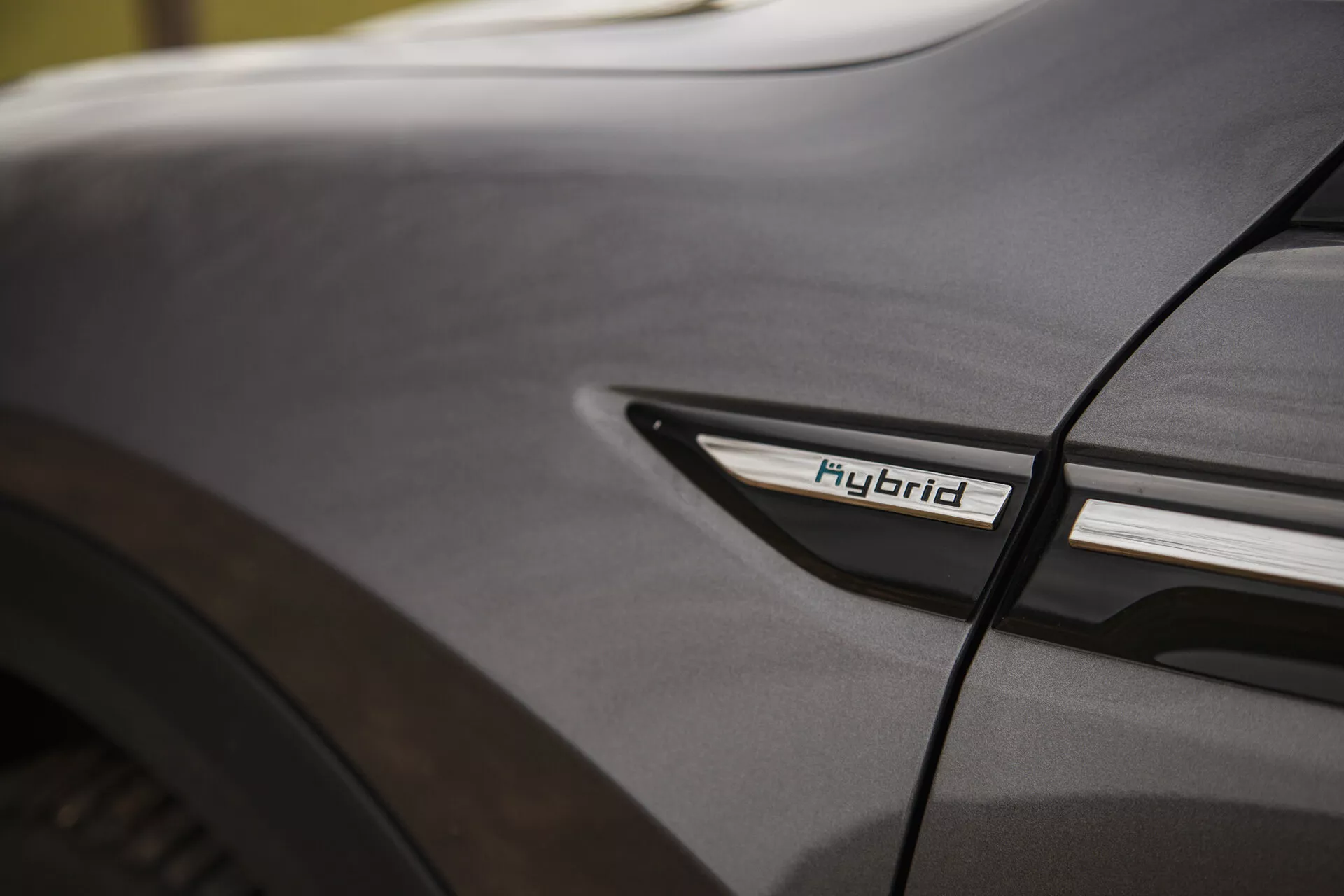 Natančen detajl Citroena C5-X 2022 s hibridnim znakom na spodnjem stranskem profilu blizu zadnjega kolesa, ki predstavlja hibridno tehnologijo in estetiko oblikovanja v mehkih svetlobnih pogojih