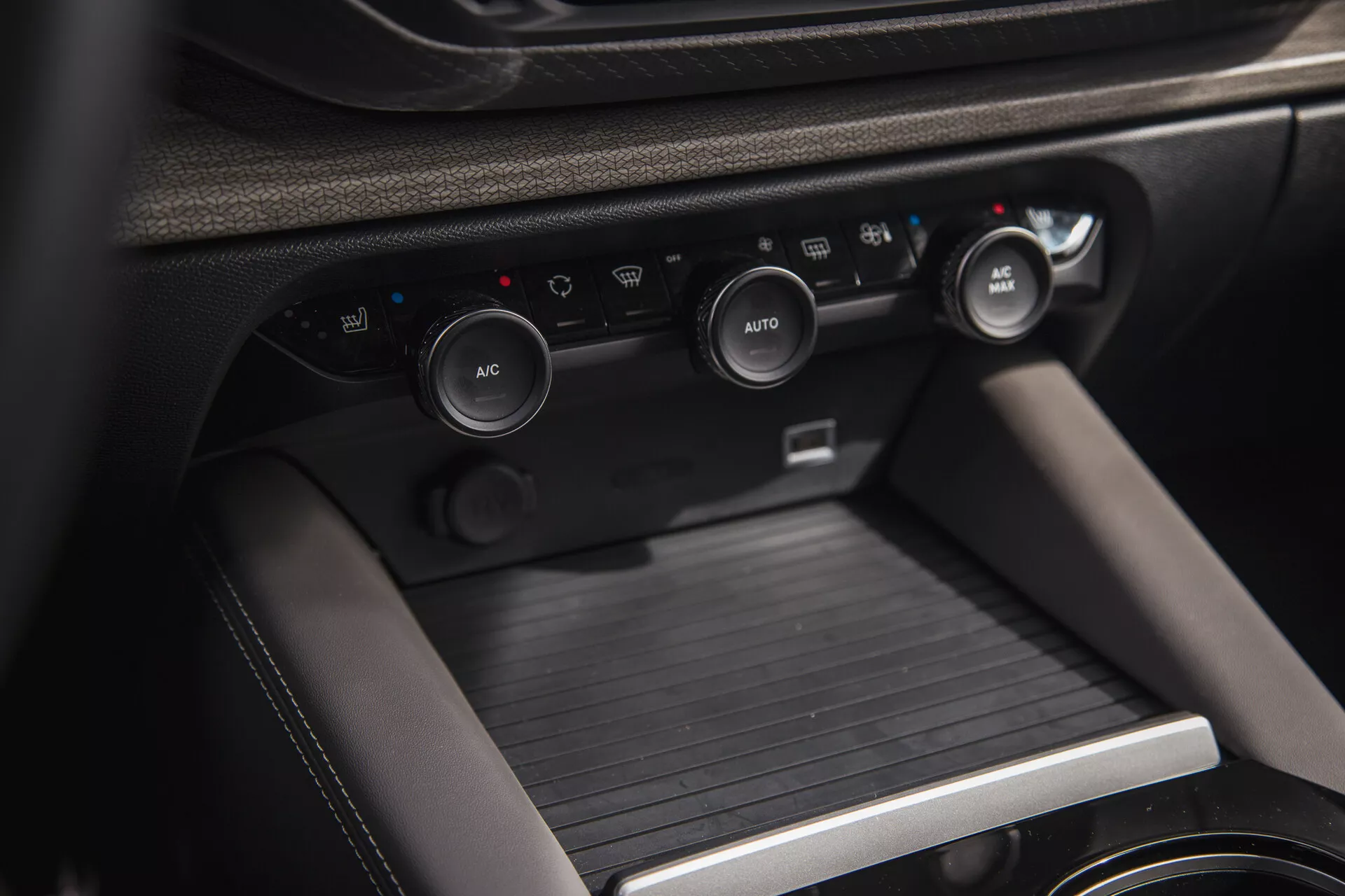Pogled od blizu na notranjost Citroen C5-X 2022, ki prikazuje sredinsko konzolo z gumbi za nadzor klime in konzolo za prestavljanje, poudarjajoč napreden klimatski sistem vozila, rešitve za shranjevanje in premijske materiale.