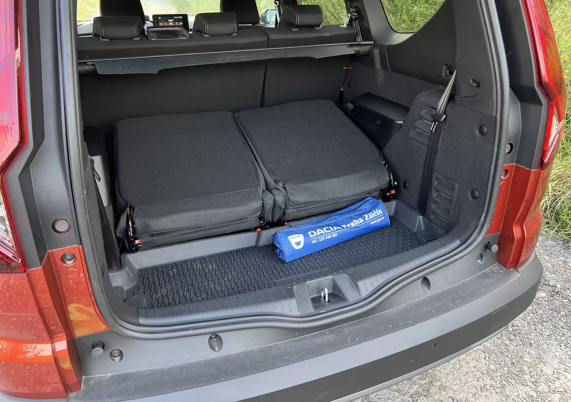 Podrobnosti prtljažnika Dacia Jogger 2022, ki prikazuje odprt tovorni prostor s preklopljenimi zadnjimi sedeži, tekstilnimi zankami za pritrjevanje predmetov in modrim valjem Decaux na preprogi