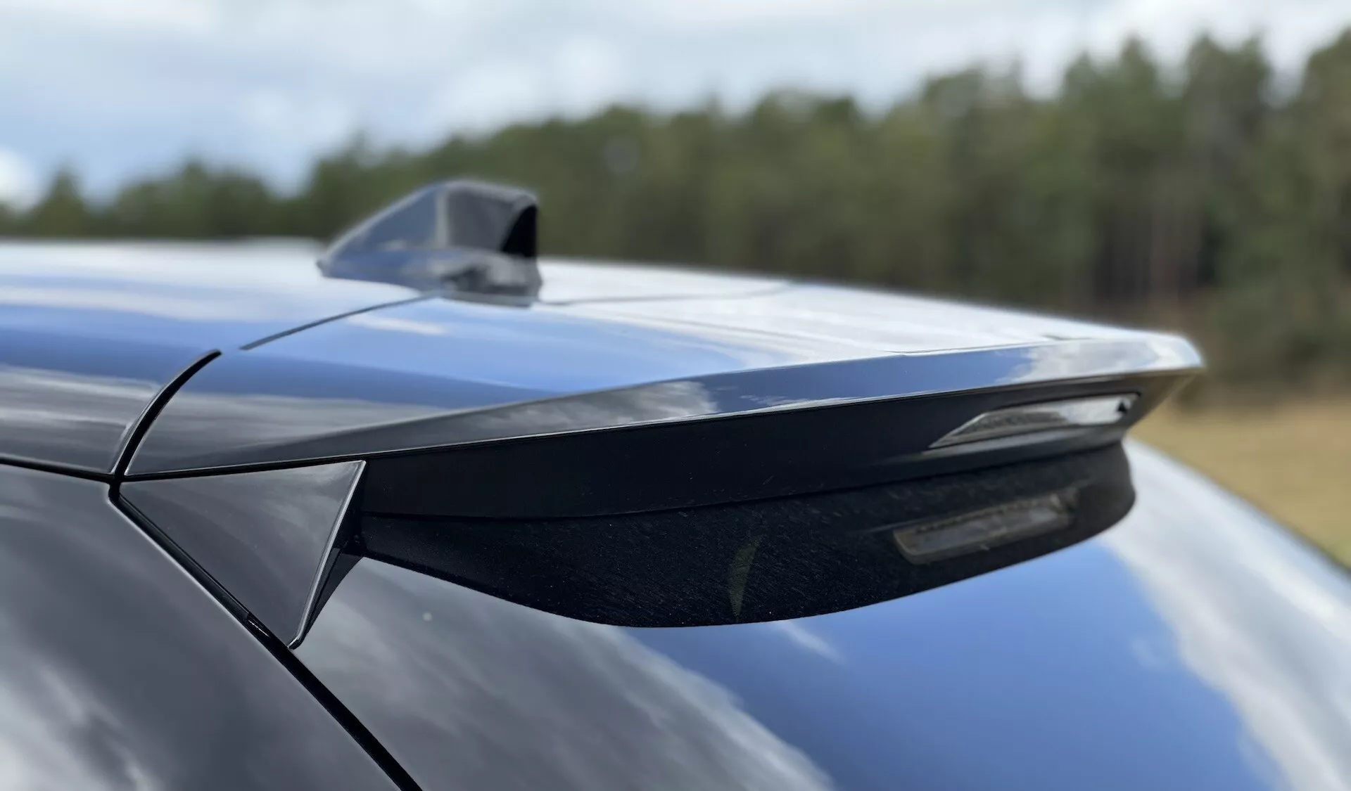 Podroben pogled na zadnji spojler in anteno v obliki morskega psa DS Automobiles DS-3 2023, ki poudarja aerodinamično obliko in kovinsko modro površino, posnet z nizkega kota v smeri spredaj