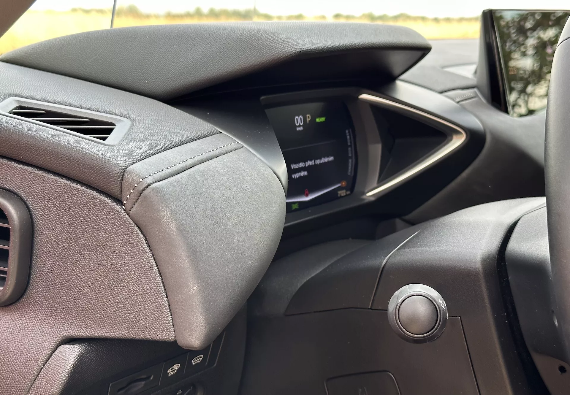 Notranji pogled na DS Automobiles DS-3 E-TENSE 2023, usmerjen na armaturno ploščo na strani voznika, vključno z usnjenim volanom s šivi in kontrolnimi gumbi, sodobnim digitalnim instrumentnim zaslonom in sistemom za zagon na gumb, ki poudarja napredno avtomobilsko tehnologijo in ergonomijo vožnje.